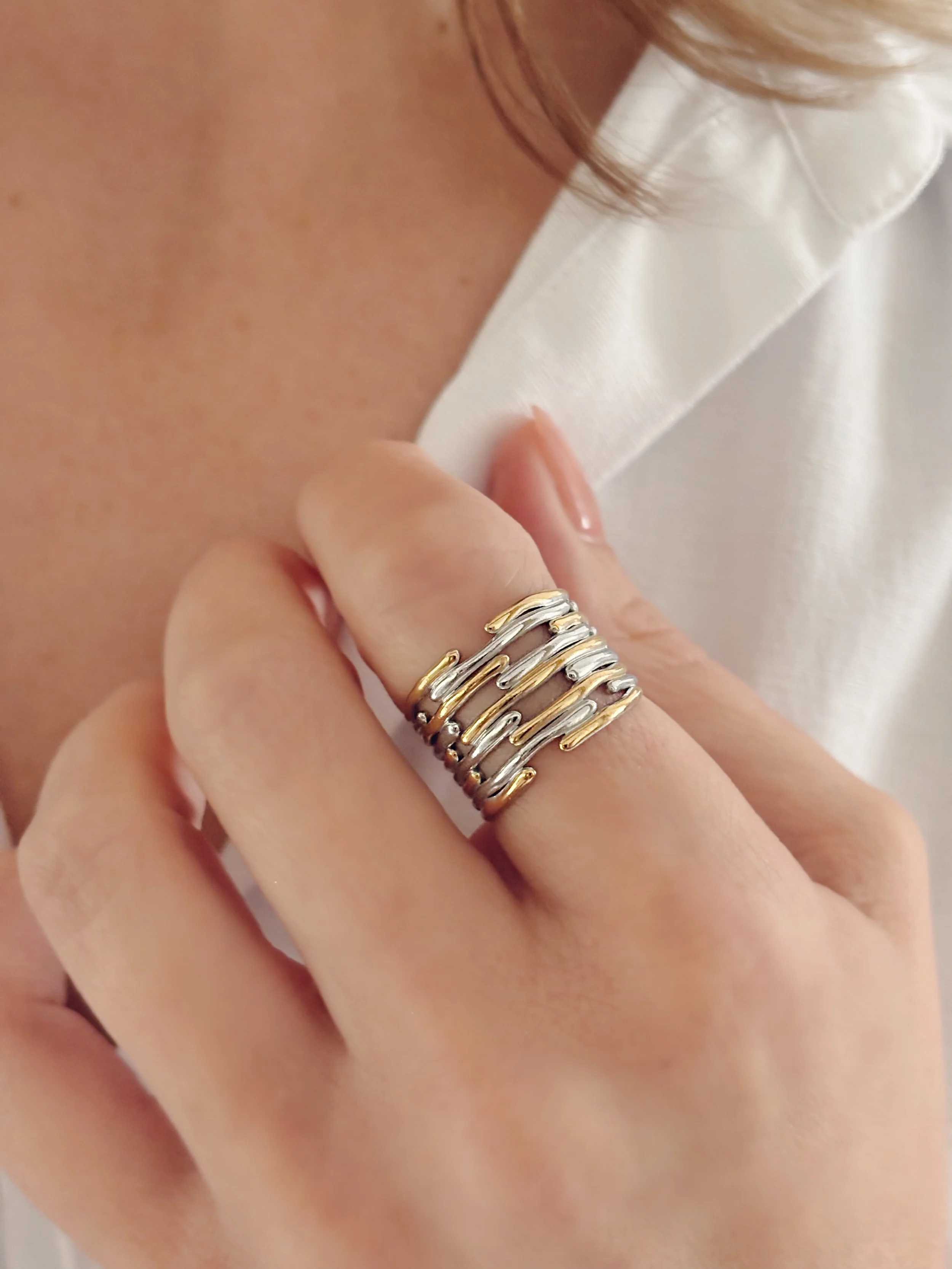 La bague Aurora portée au doigt, mettant en valeur son design argenté et doré.