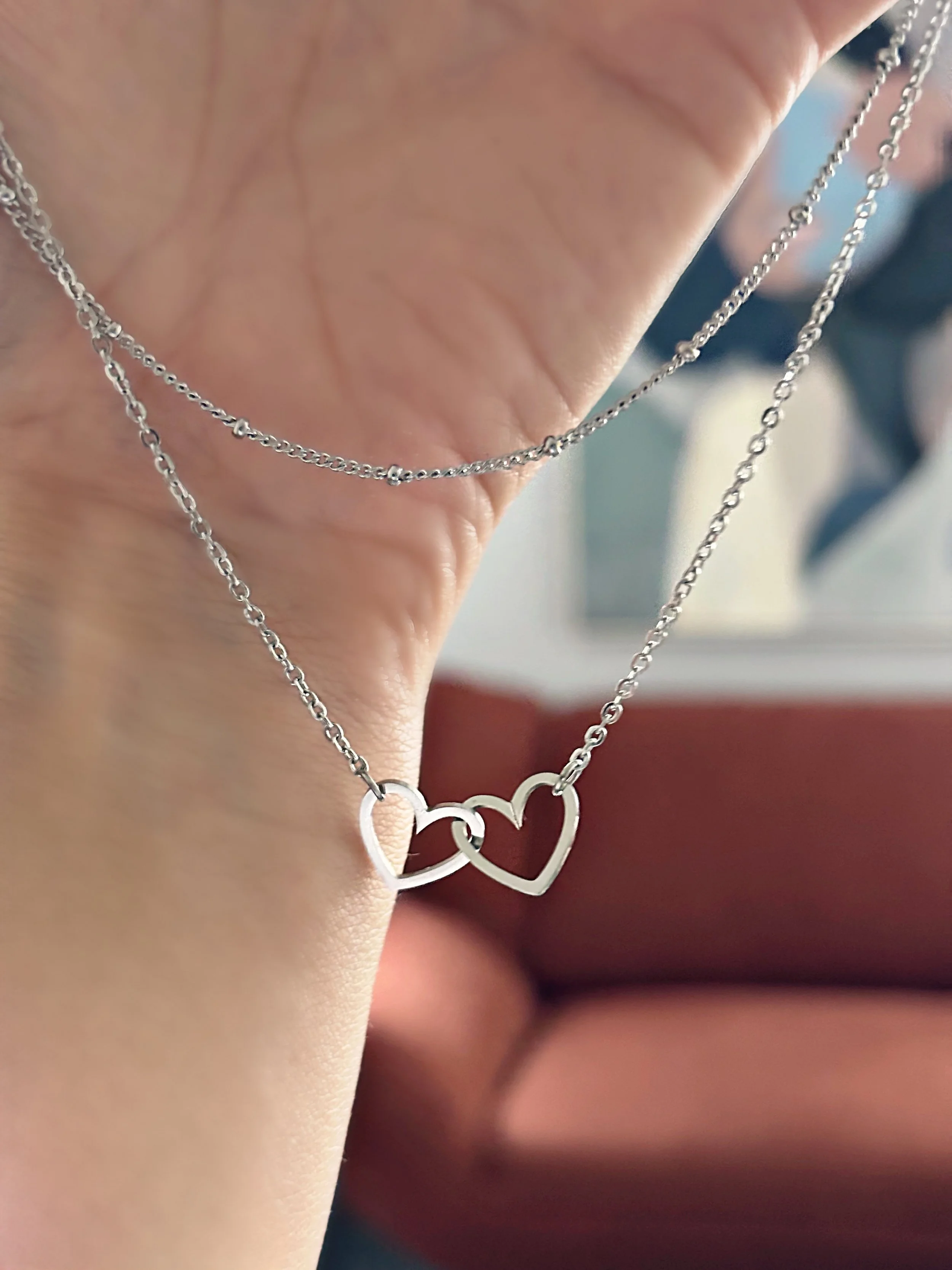 Vue rapprochée du collier Kalia posé sur une surface douce, mettant en valeur le design romantique et les deux cœurs entrelacés.