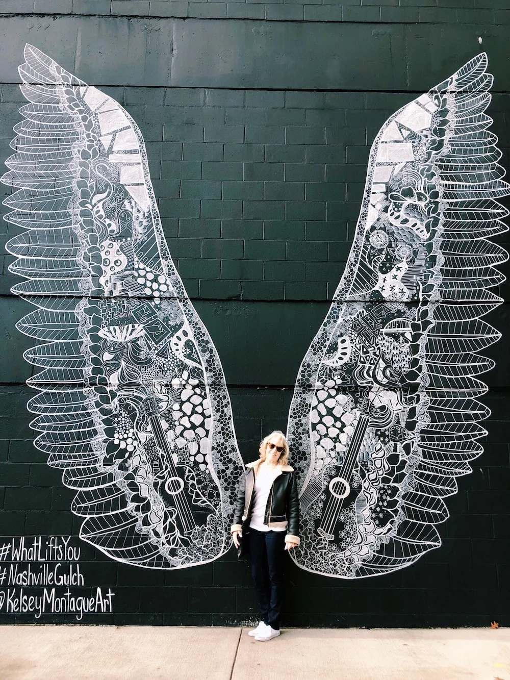 Woman in front of black and white wing mural