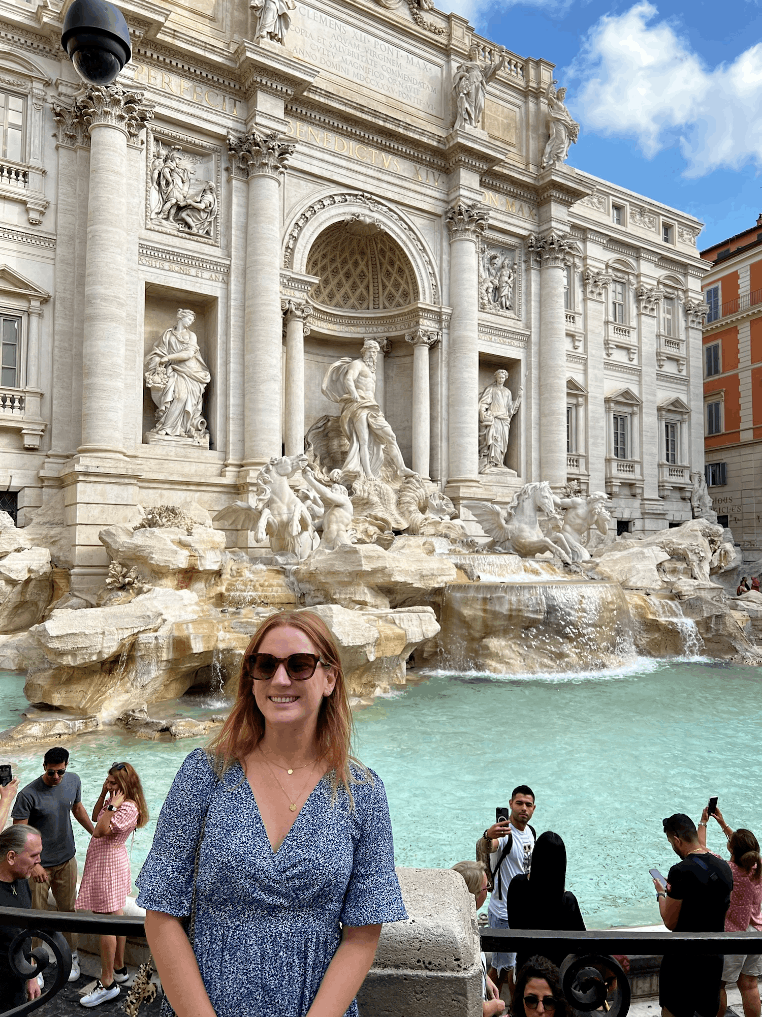 woman in blue dress in front of the trevi fountain in rome italy