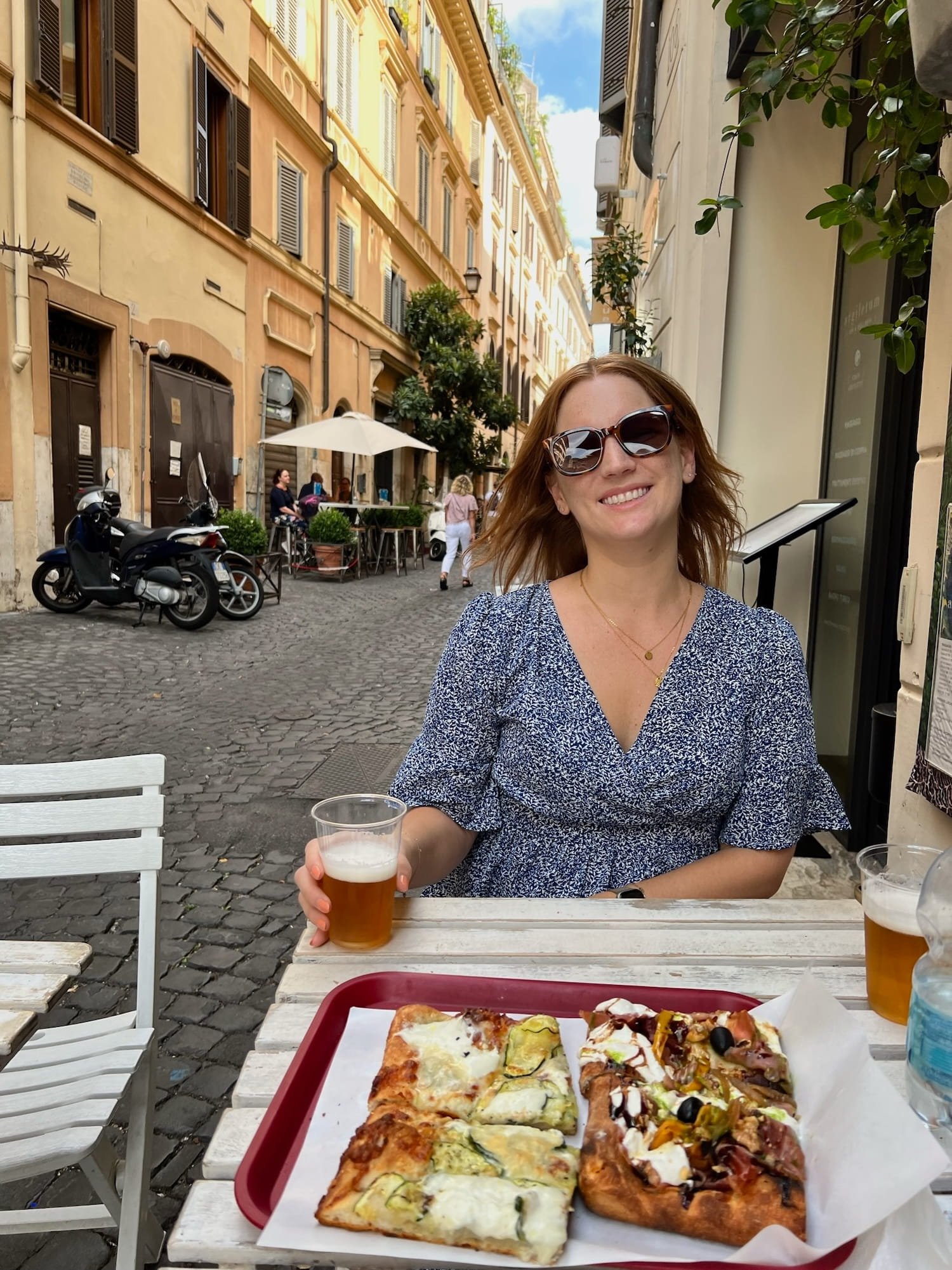woman on terrace eating square roman style pizza with zucchini