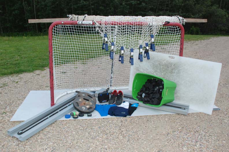 Except for the sports netting hanging over the top of the goal, which I replaced with the goal itself, all the items pictured here see regular service in the course of my training exploits. The grey L-shaped device is the Powerskater skating machine. In the foreground in front of the barbell plates are various practice pucks and balls, my trusty gym timer and two tiny badges I earned at a powerskating course.