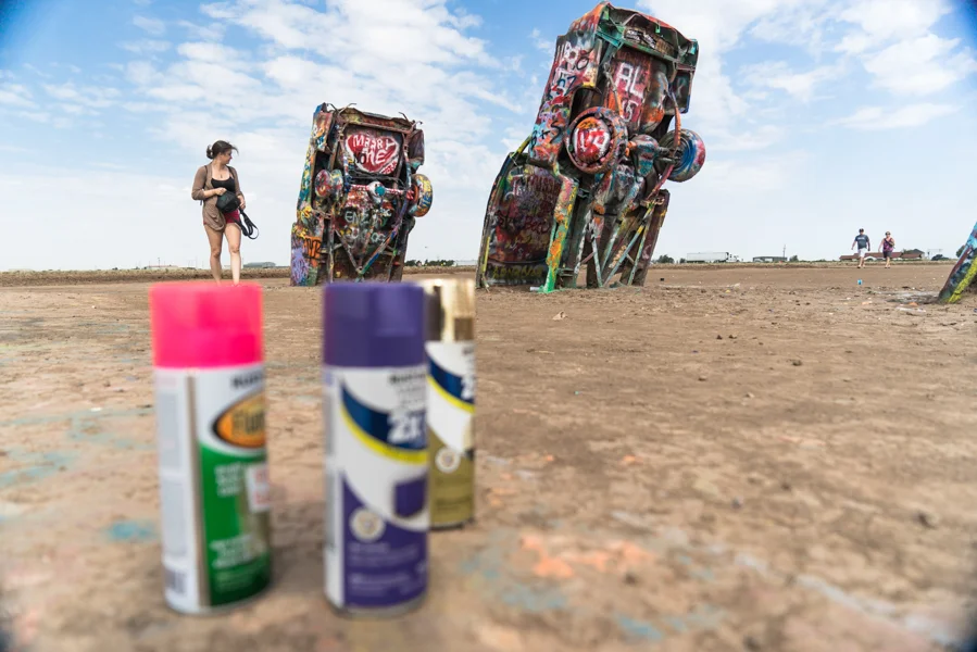 Cadillac Ranch, Amarillo, TX Cadillac Ranch is one of those places that screams tourist trap. The place is a great stop to break up the monotony of a long drive, however, due to its interactivity. People are encouraged to take part in the piece and spray paint their own pieces onto the cars. We did not happen to bring paint with us, but other visitors were more than happy to share their unused supplies with us. We took some time to climb around and leave our own touch on a few of the cars.