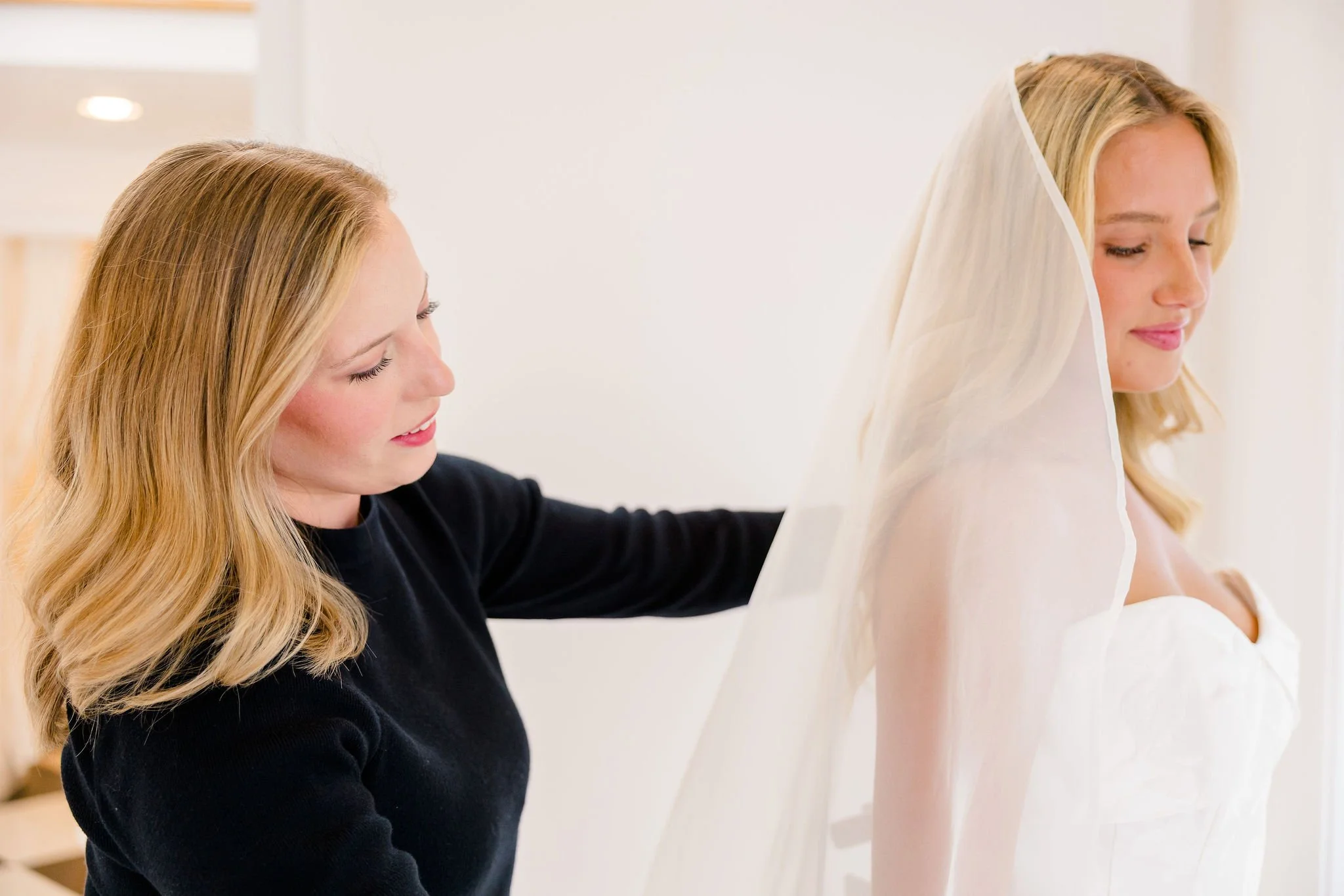 A bridal stylist assists a bride in putting on a veil at House of White Bridal Boutique in Newburgh, Indiana.
