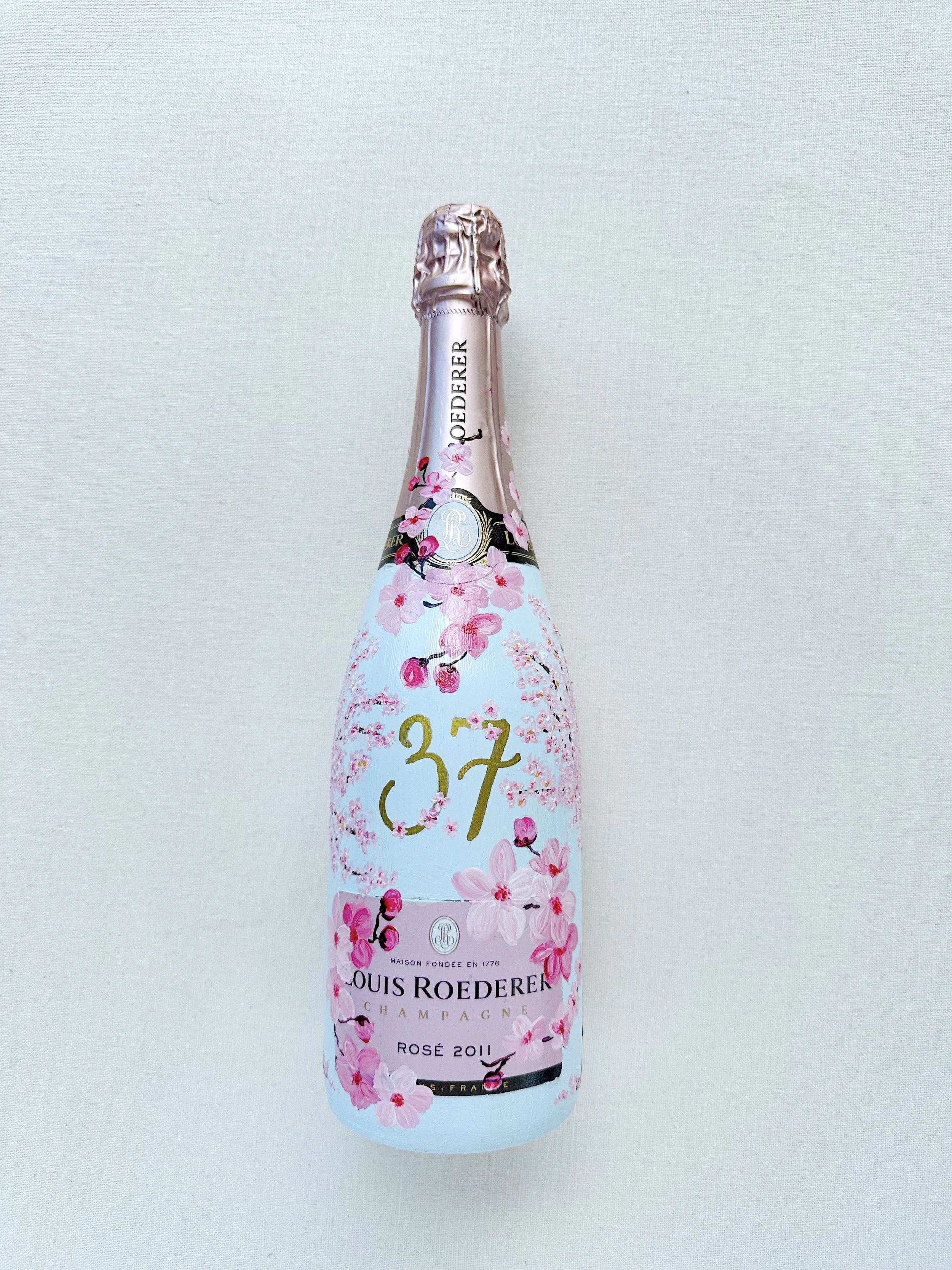 A bottle of Louis Roederer Champagne with a pink floral design hand painted