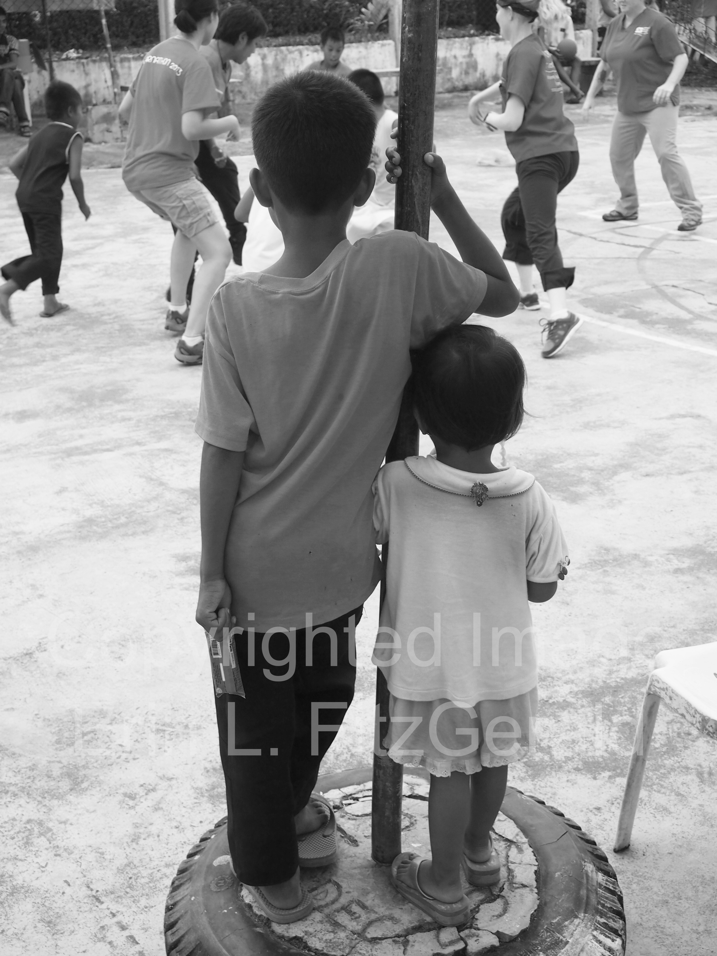   Two children watch as healthcare workers join with the local community for a post-clinic game of soccer.  