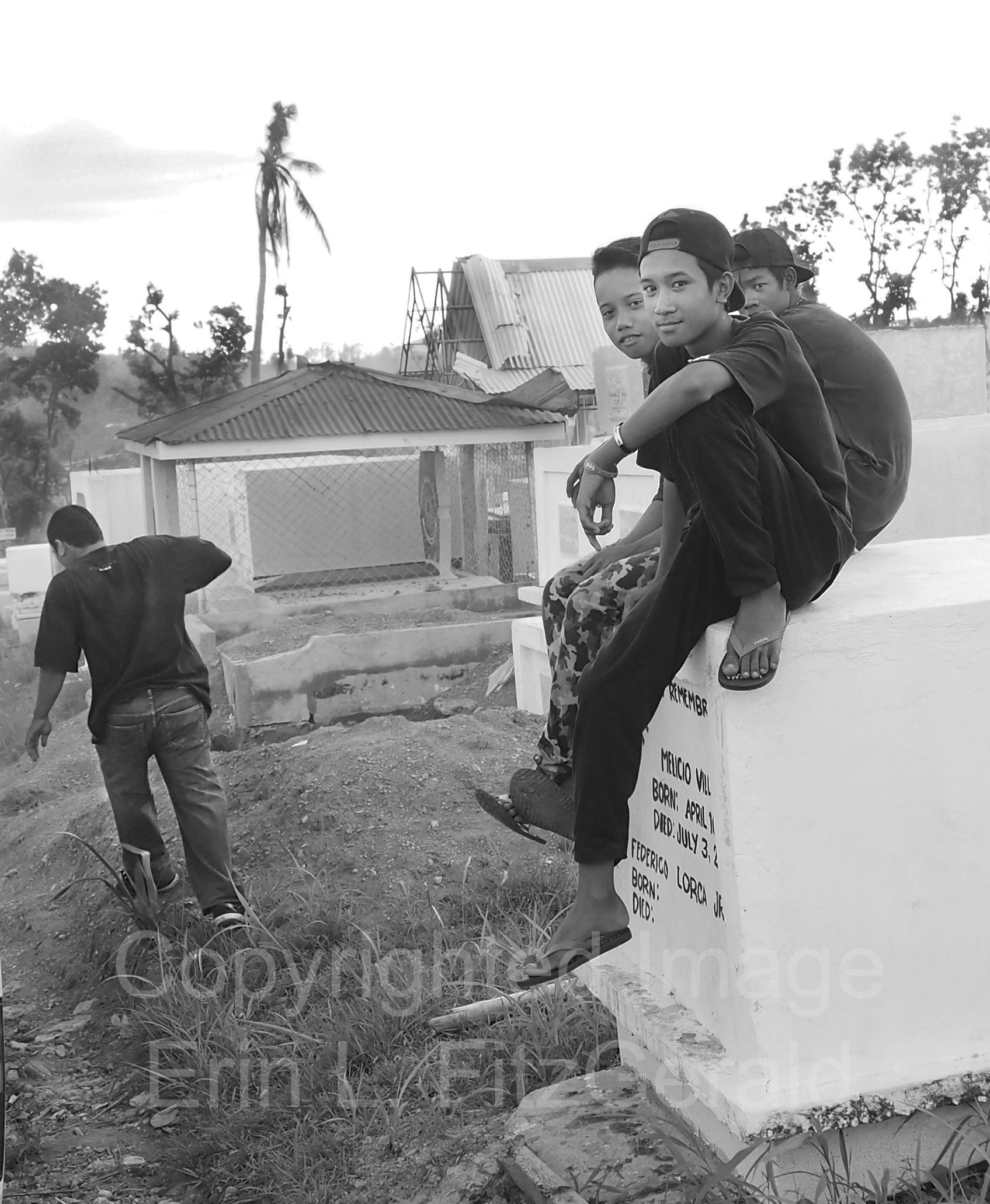  Boys sit on a headstone after leading nurses to an unmarked grave containing unidentified victims of Typhoon Haiyan. 