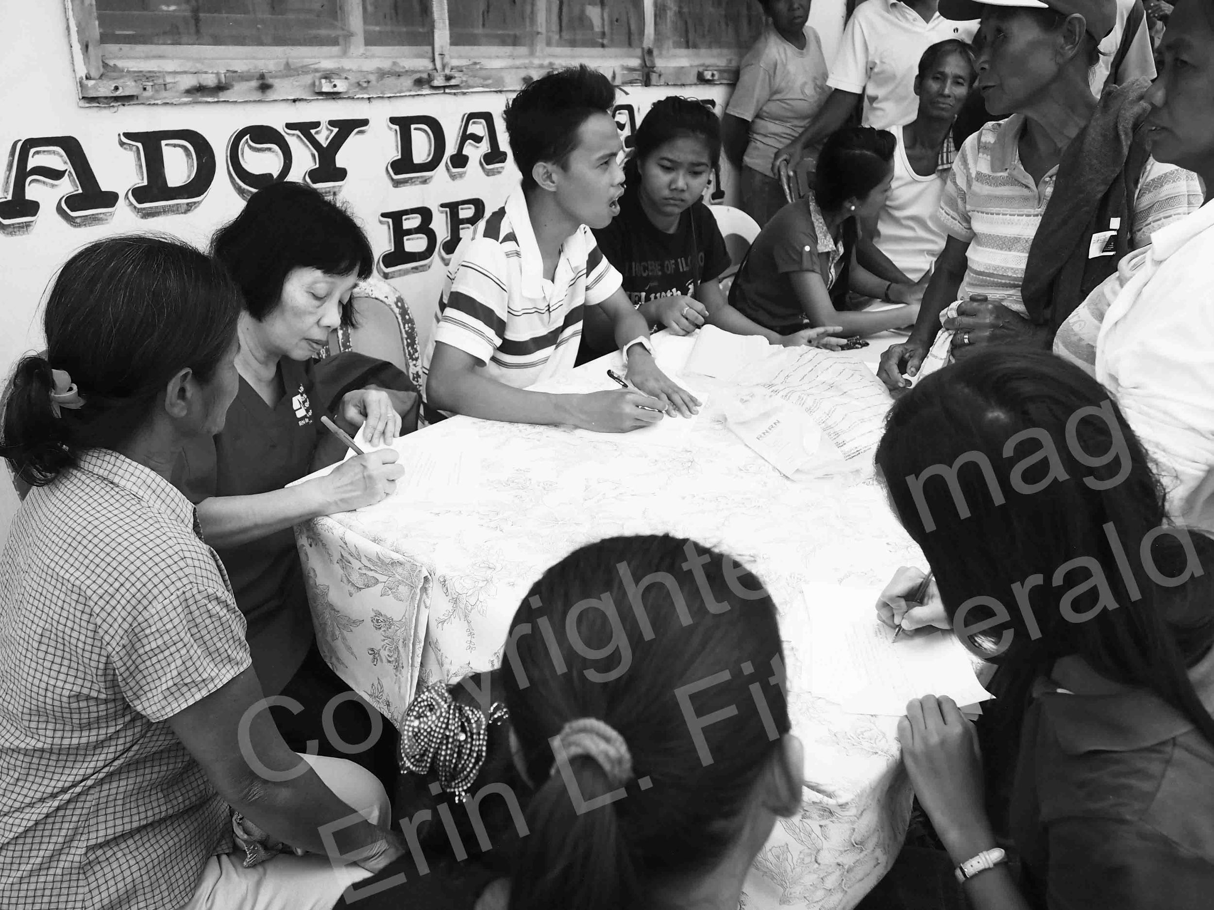  Families in need of care surround a table set up to register Typhoon Haiyan survivors for health screenings. NNU's RN Response Network worked with caregivers from the Philippines and Singapore to deliver aid to coastal cities in Estancia following t