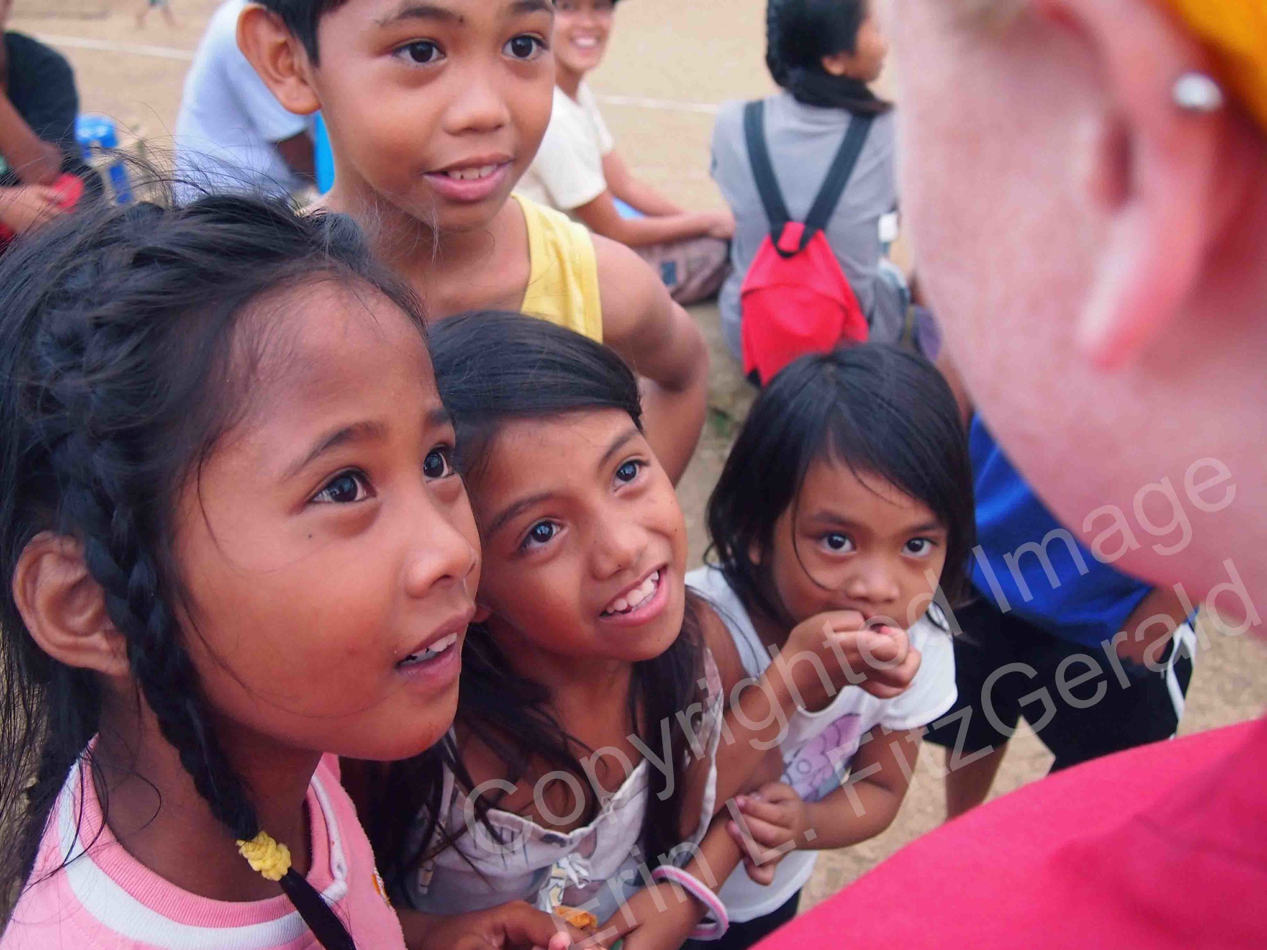  Children at a refugee center gather around a nurse visiting from the United States. The girls were brought to the center after their homes were damaged by Typhoon Haiyan in November 2013.  