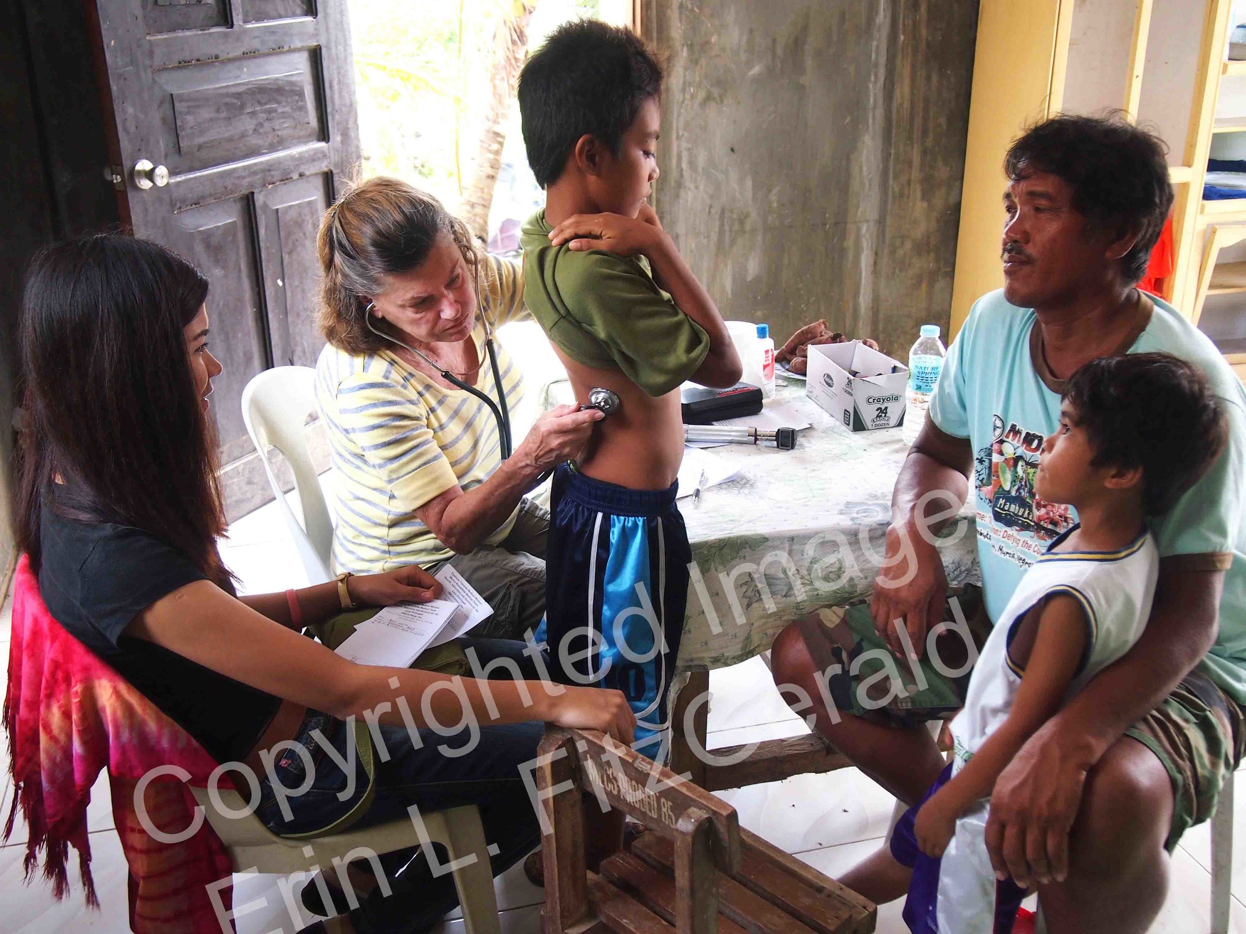   Nurse Practitioner Betty Woods evaluates families in a classroom converted to a clinic to serve locals devastated by Typhoon Haiyan.  