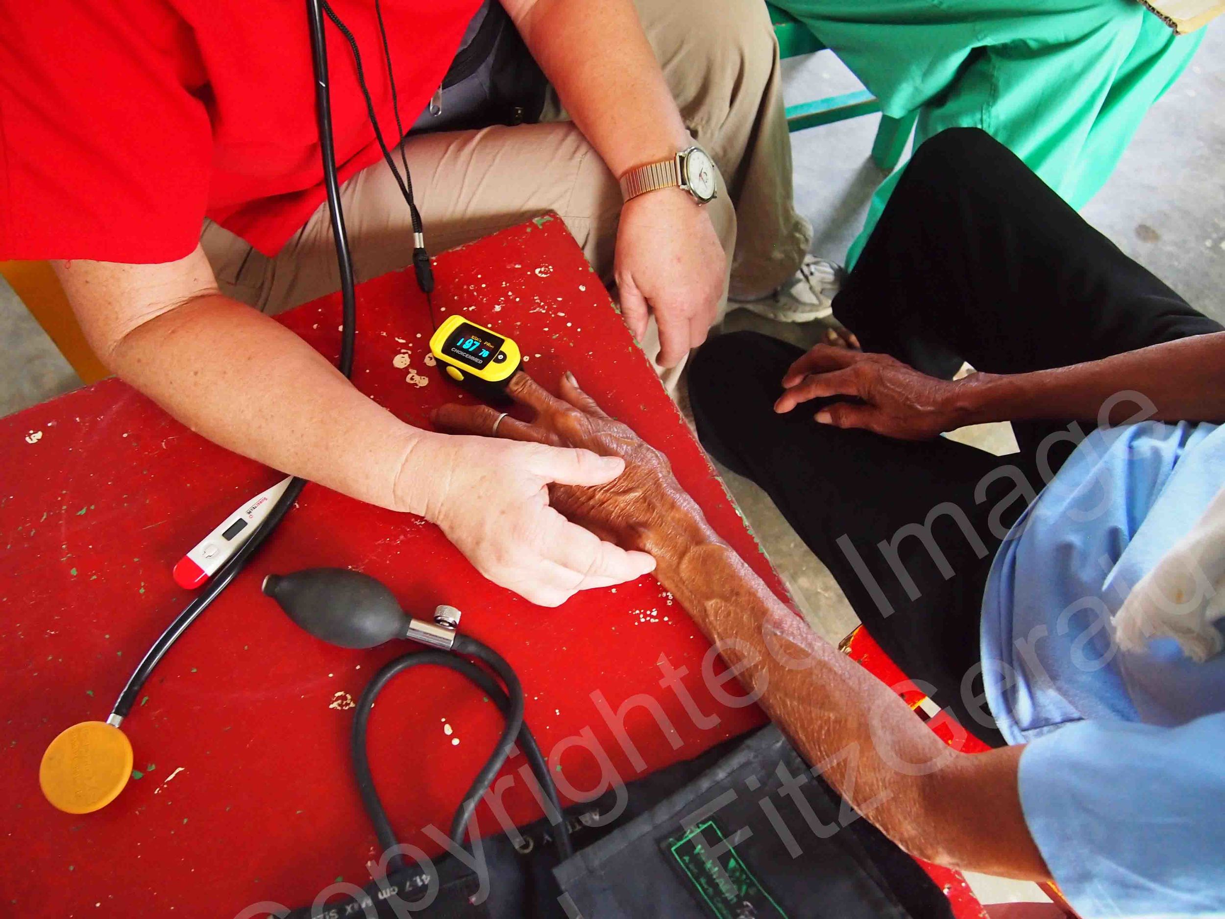   A nurse evaluates a woman's health after her neighborhood is devastated by Typhoon Haiyan.  