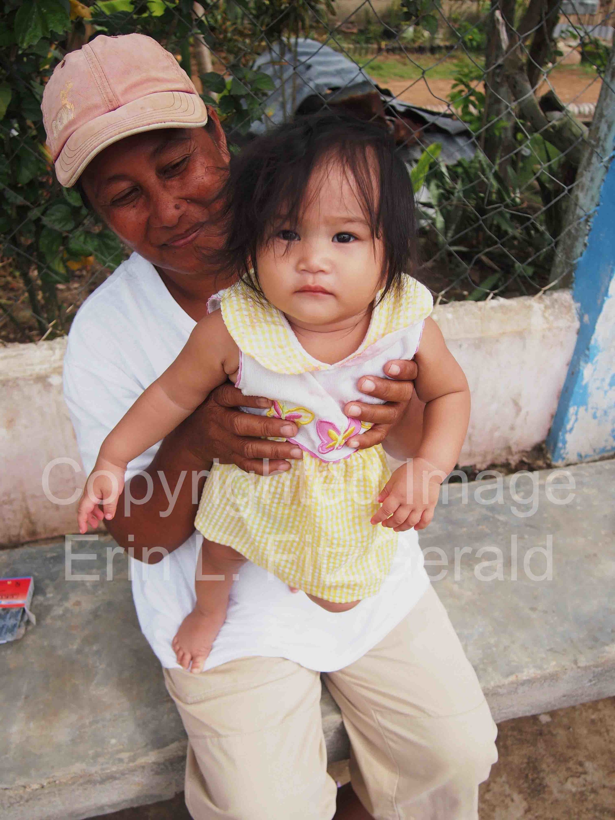   A mother shows off her baby while waiting for care at a makeshift clinic staffed by relief nurses.  