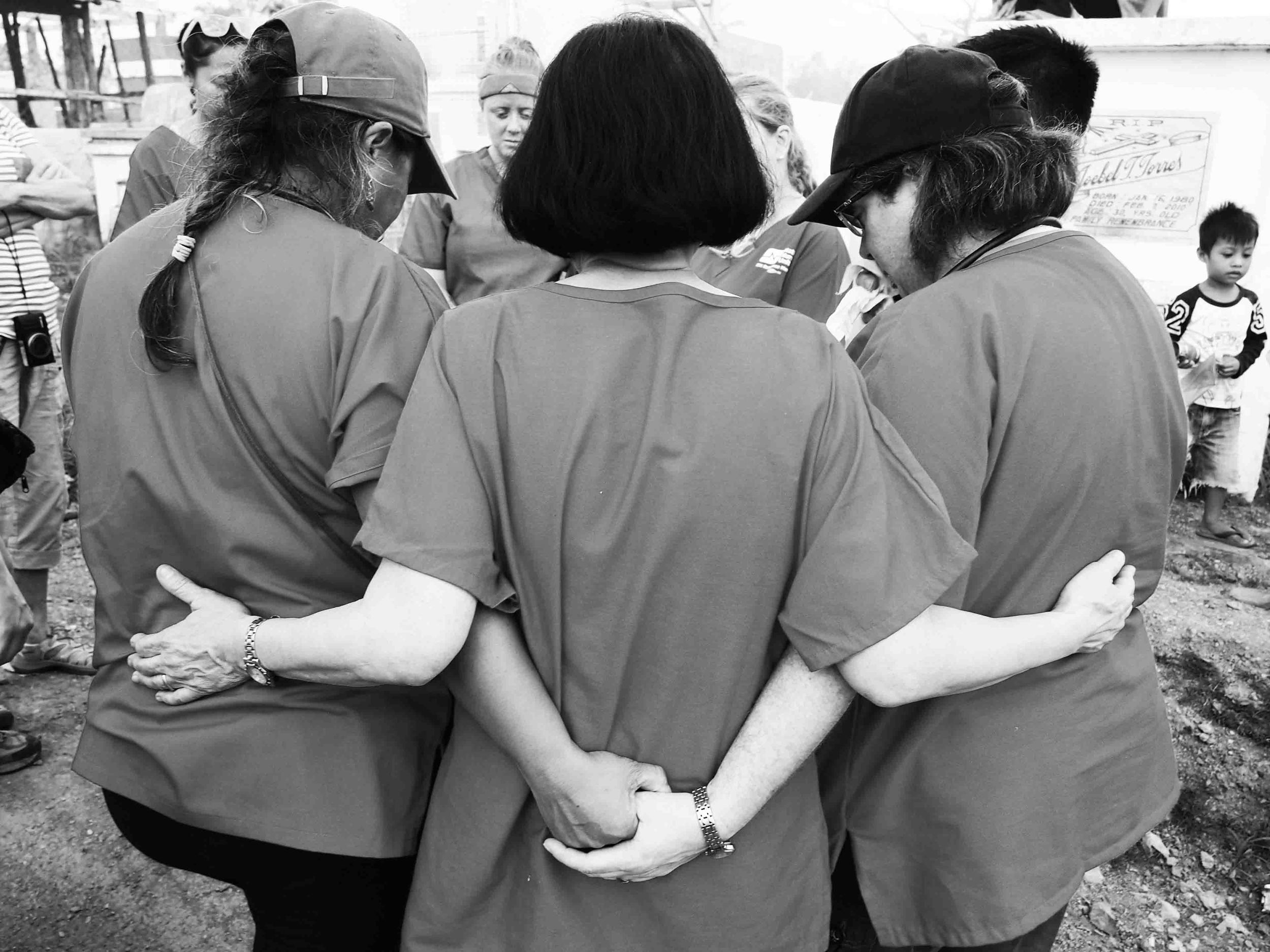   Nurses join hands and bow their heads to pay their respects at a mass grave containing unidentified victims of Typhoon Haiyan.&nbsp;  