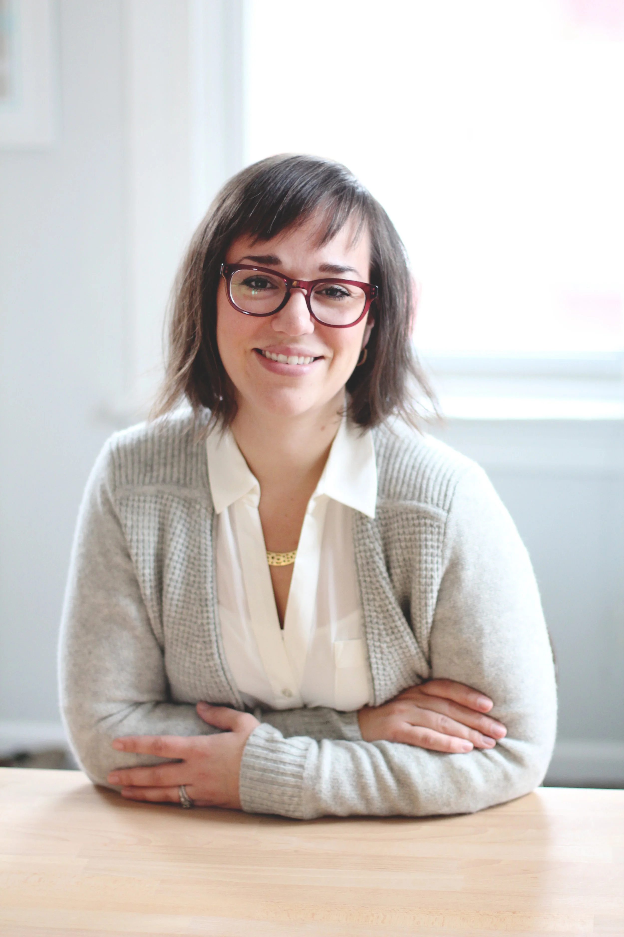 lady smiling with arms folded in front of her wearing glasses