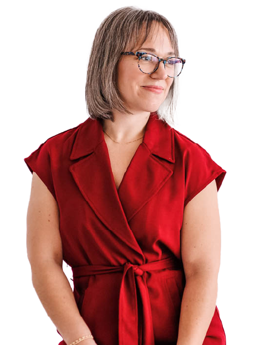 Woman with shoulder-length gray hair, glasses, wearing a red sleeveless wrap dress, smiling softly.