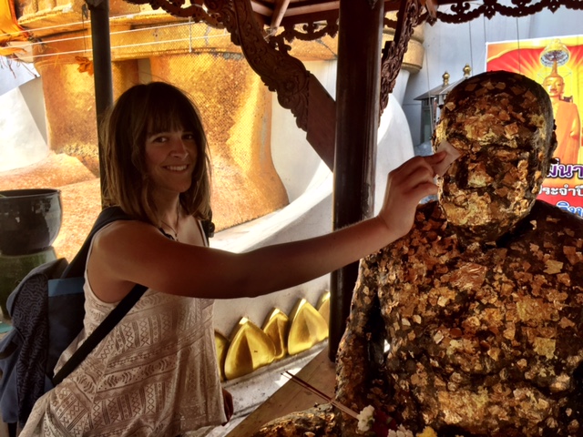 Putting gold leaf on a statue in the temple.