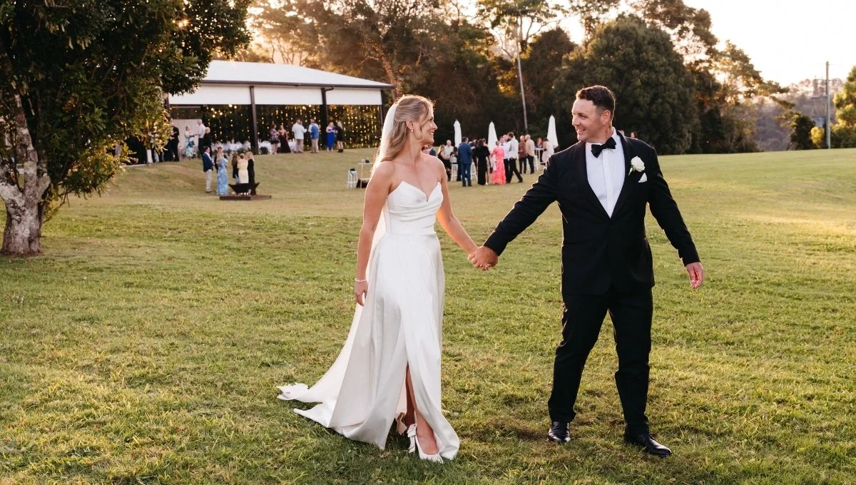 Elysian-Hills-bride-and-groom-walking-on-an-open-grassy-field.jpg