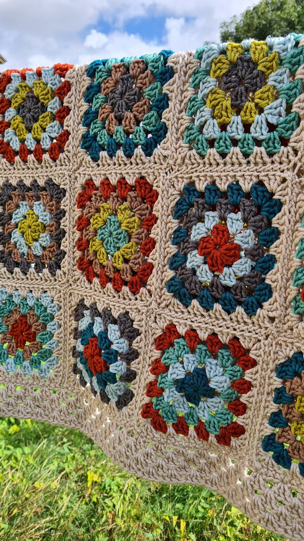 Chunky crochet square blanket by Louise Tilbrook. Image shows a large blanket hanging from a washing line on a sunny day. 