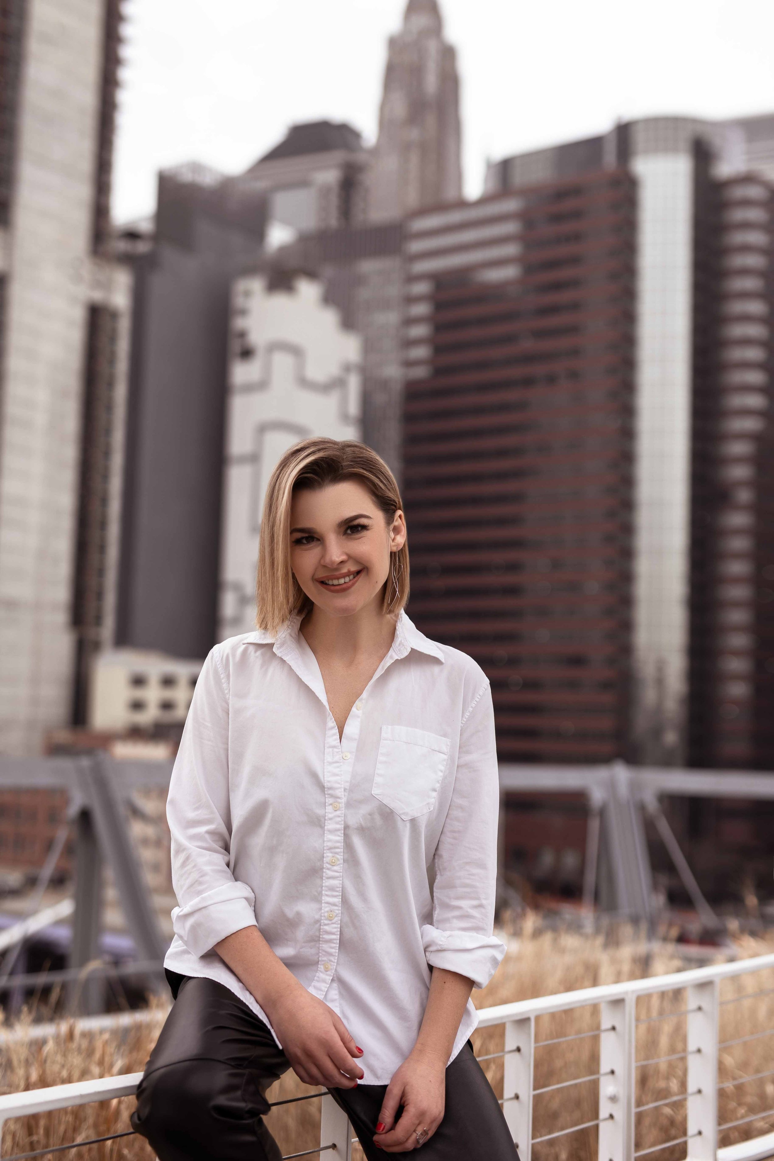 Creative business owner laughs naturally during an outdoor branding shoot, wearing white shirt.