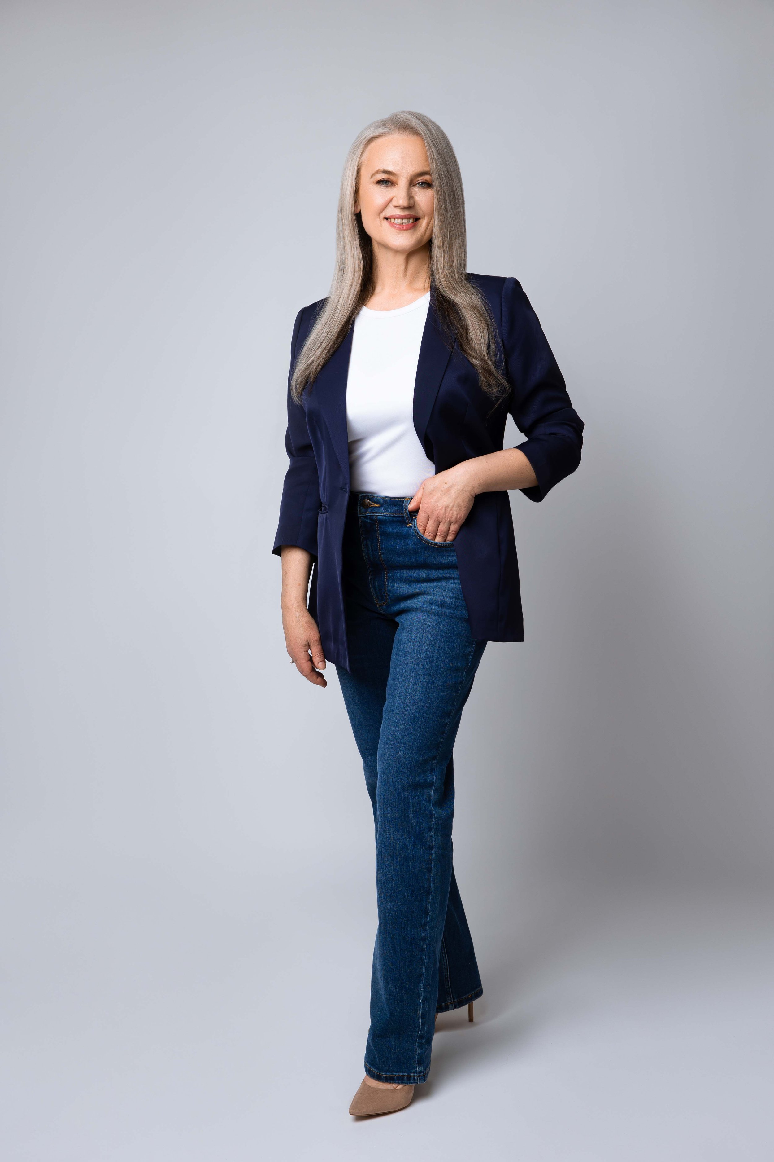 Female entrepreneur stands confidently in a minimalist studio setting during modern headshot for branding.