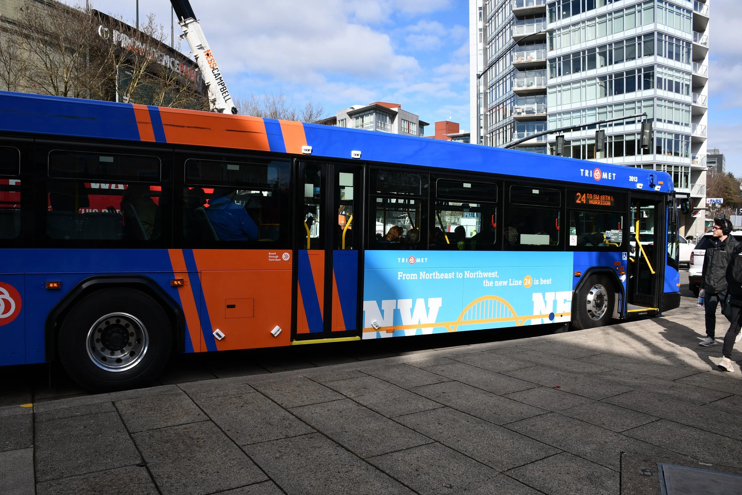  TriMet bus with smaller-sized ad on side with text: “From Northeast to Northwest, the new Line 24 is best.” 
