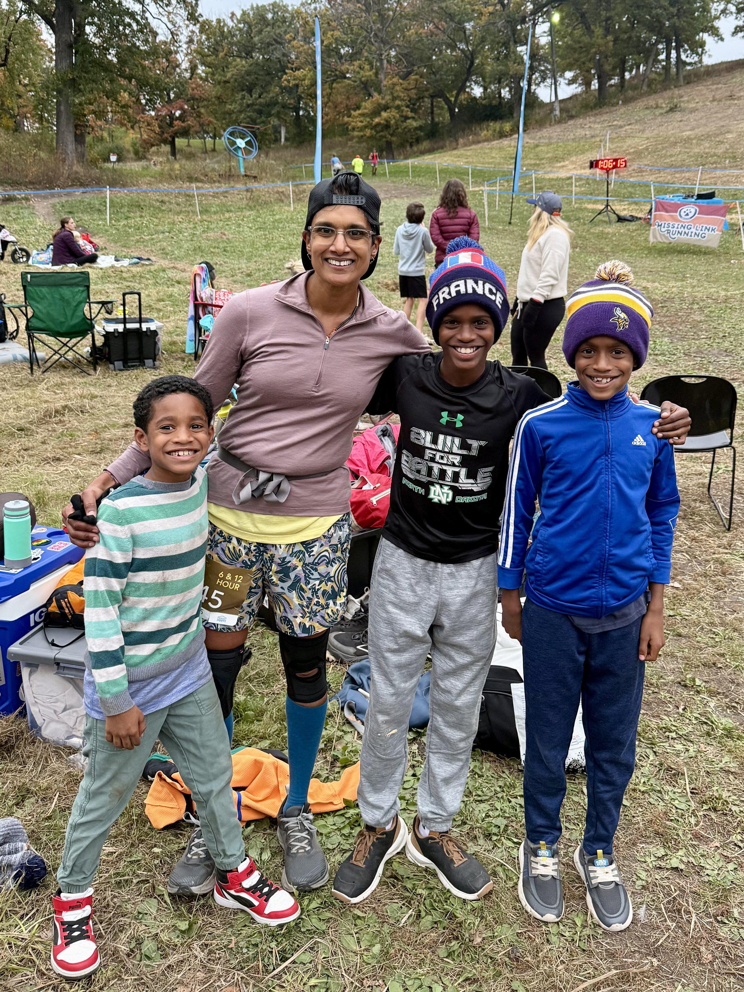 3 Blindian nephews with their queer South Indian Auntie, after having paced her 6 miles (totaling 22) at the 6-hour Haha Wakpadan race at Theodore Wirth Regional Park in Minneapolis in October 2025.