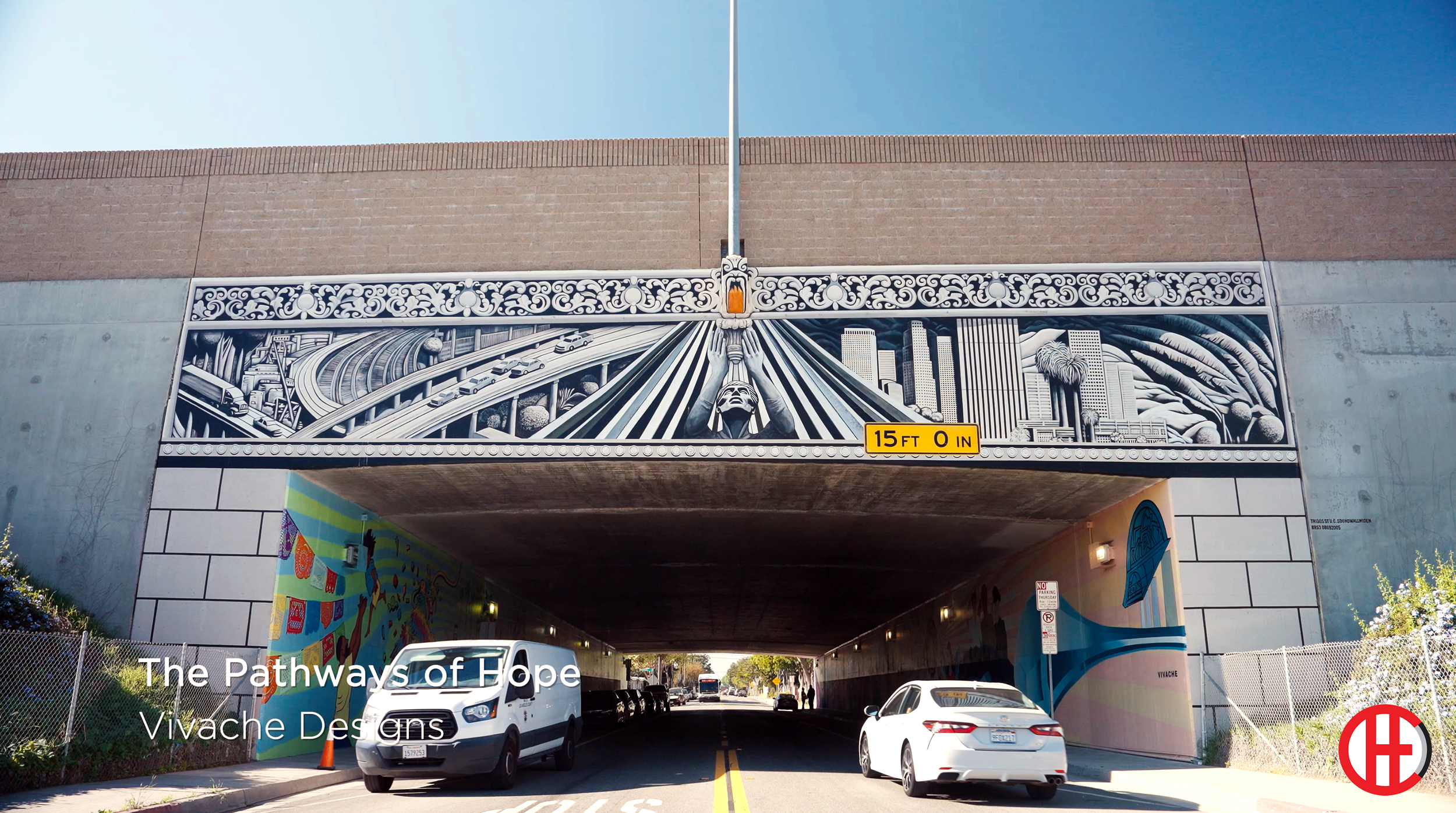 Tunnel with colorful flower mural on the walls, illuminated ceiling lights, floor with some dirt and marks, bright exit in the distance.