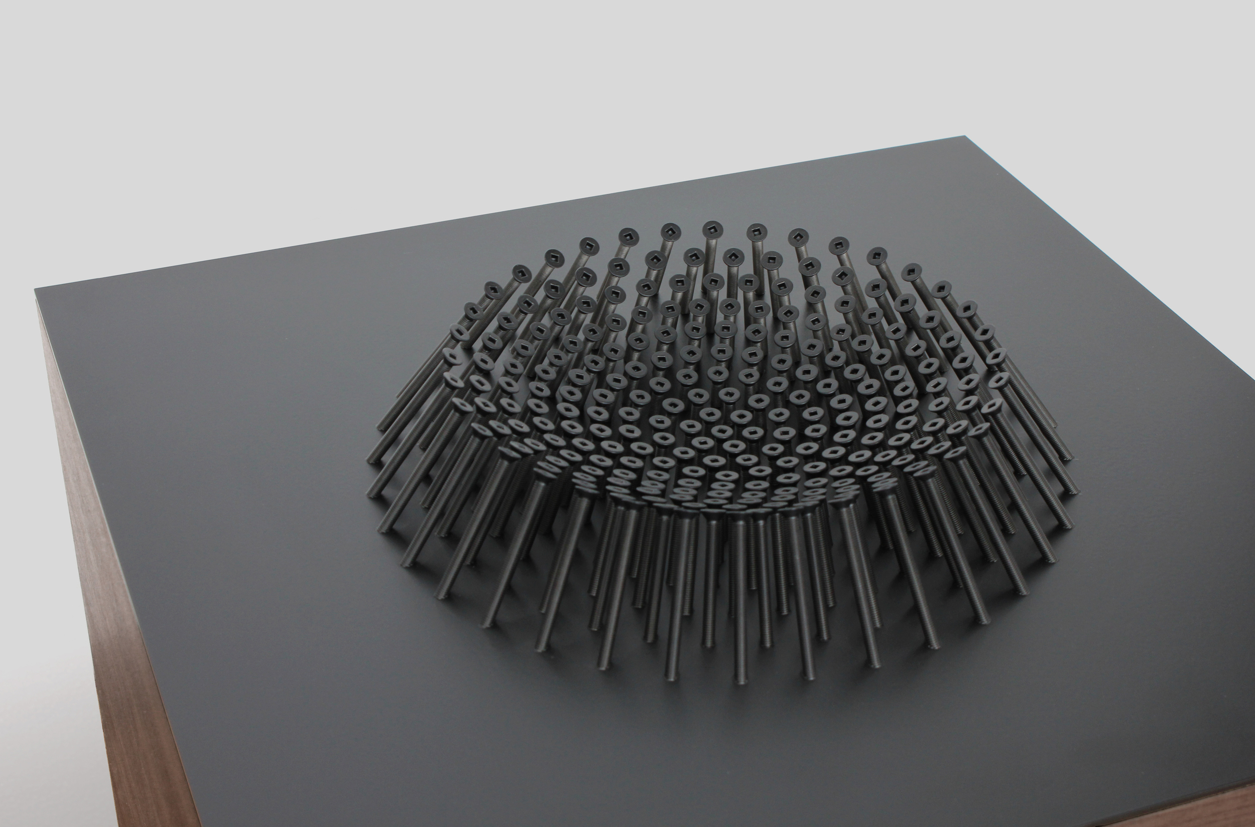 The prototypes are made with walnut veneer and plywood. for the table tops, the process begins by machining aluminum plates on a five-axis CNC mill. The machine drills and threads the holes within the intricate pattern with impressive accuracy. To f