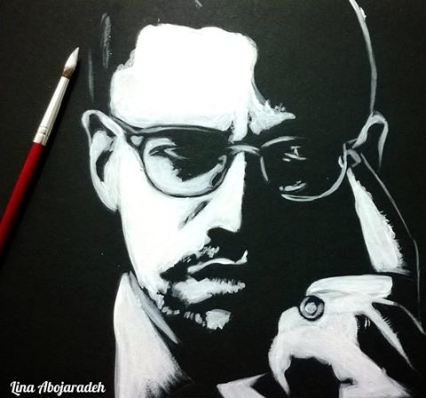 Image Description: A red, wooden small-tipped paint brush with some white paint on tip hovers over a white-on-black painting of Malcom X. Malcom has a serious look peering out through his glasses, and a finger to his temple as if in deep thought, or trying to project his thought to the object of his gaze.. This painting is a creation of Lina Abojaradeh, her signature is on the bottom left, in white.