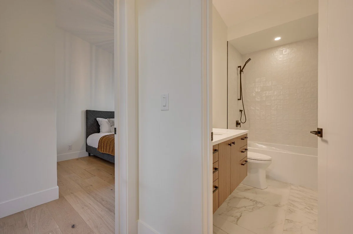 A view of a bedroom with a bed and a bathroom with a vanity, toilet, and bathtub.