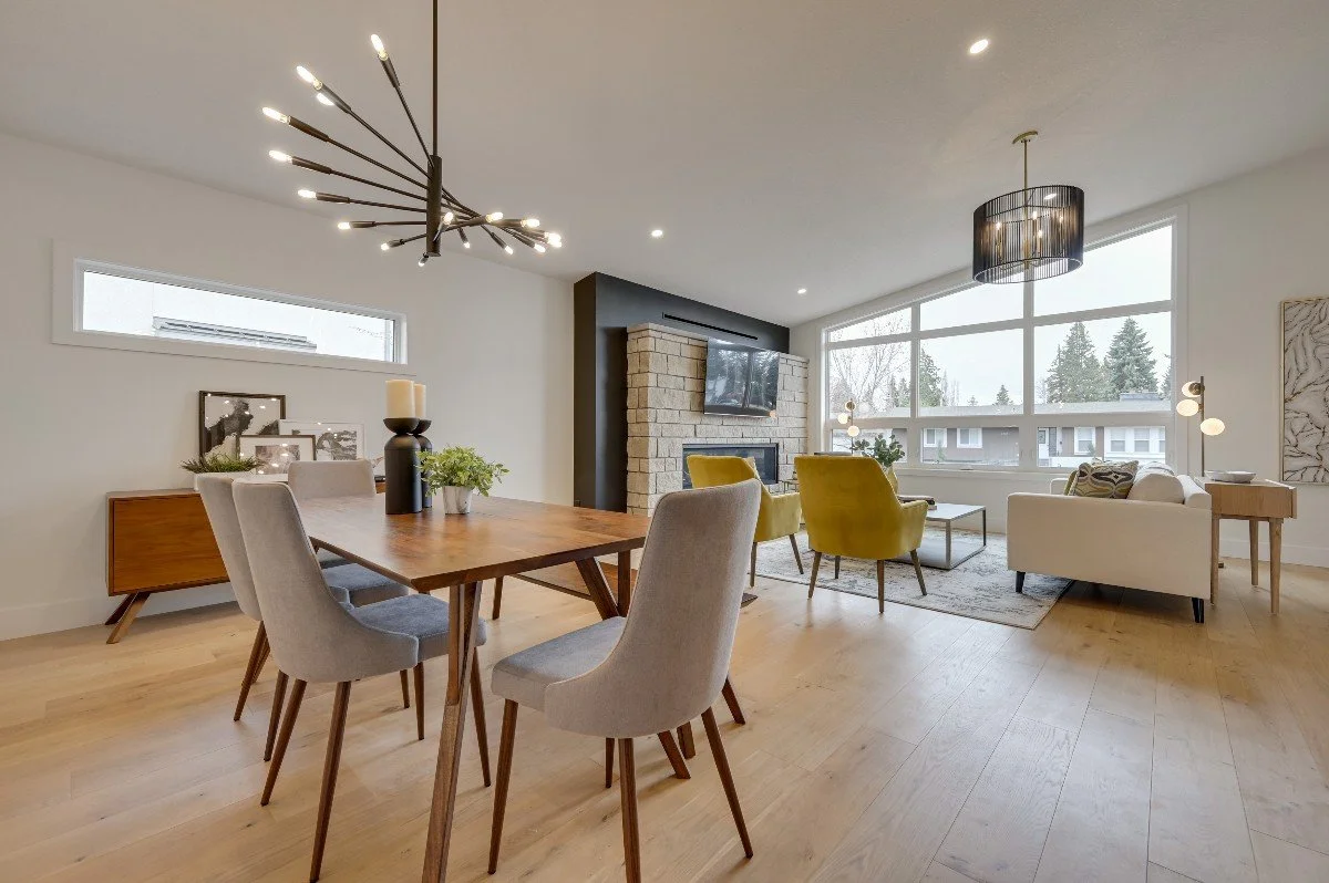 Modern living and dining room with wood floor, contemporary furniture, fireplace, large windows, and minimalist decor.