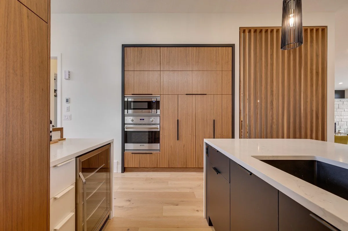 Modern kitchen with wooden cabinets, a white countertop island with a black sink, and vertical wooden slat divider.