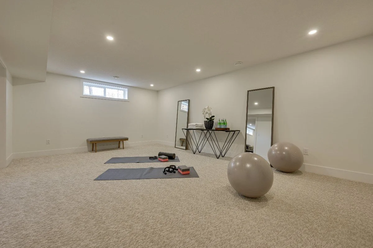 Empty fitness or yoga room with exercise mats, weights, large exercise balls, a bench, and mirrors.