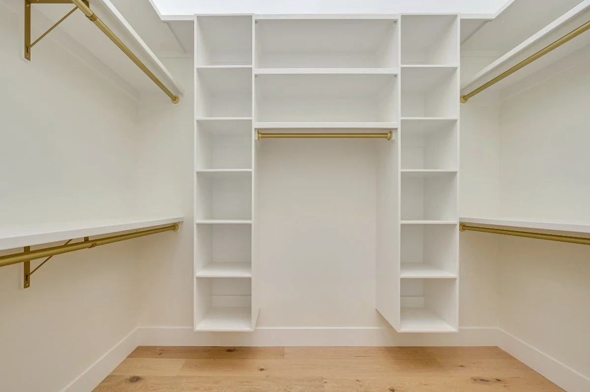 Empty walk-in closet with white shelves and hanging rods