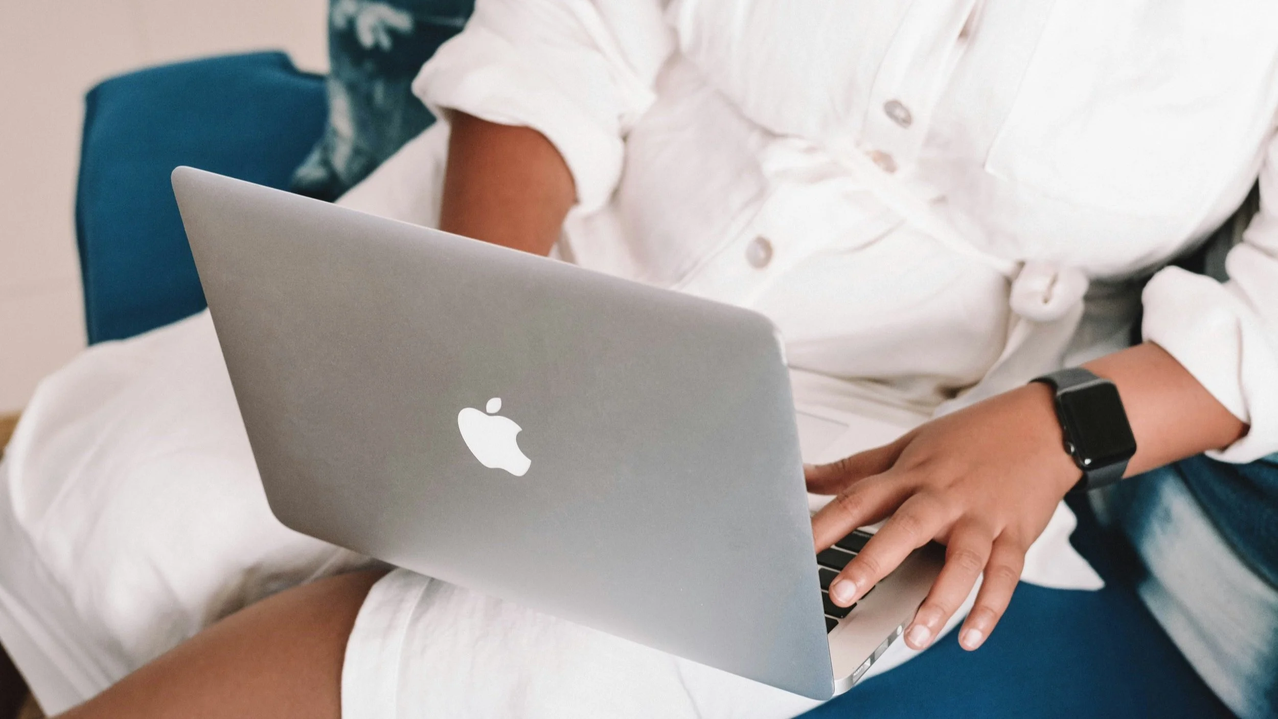 A BIPOCfemale travel advsior on your apple computer wearing white jumpsuit and apple watch