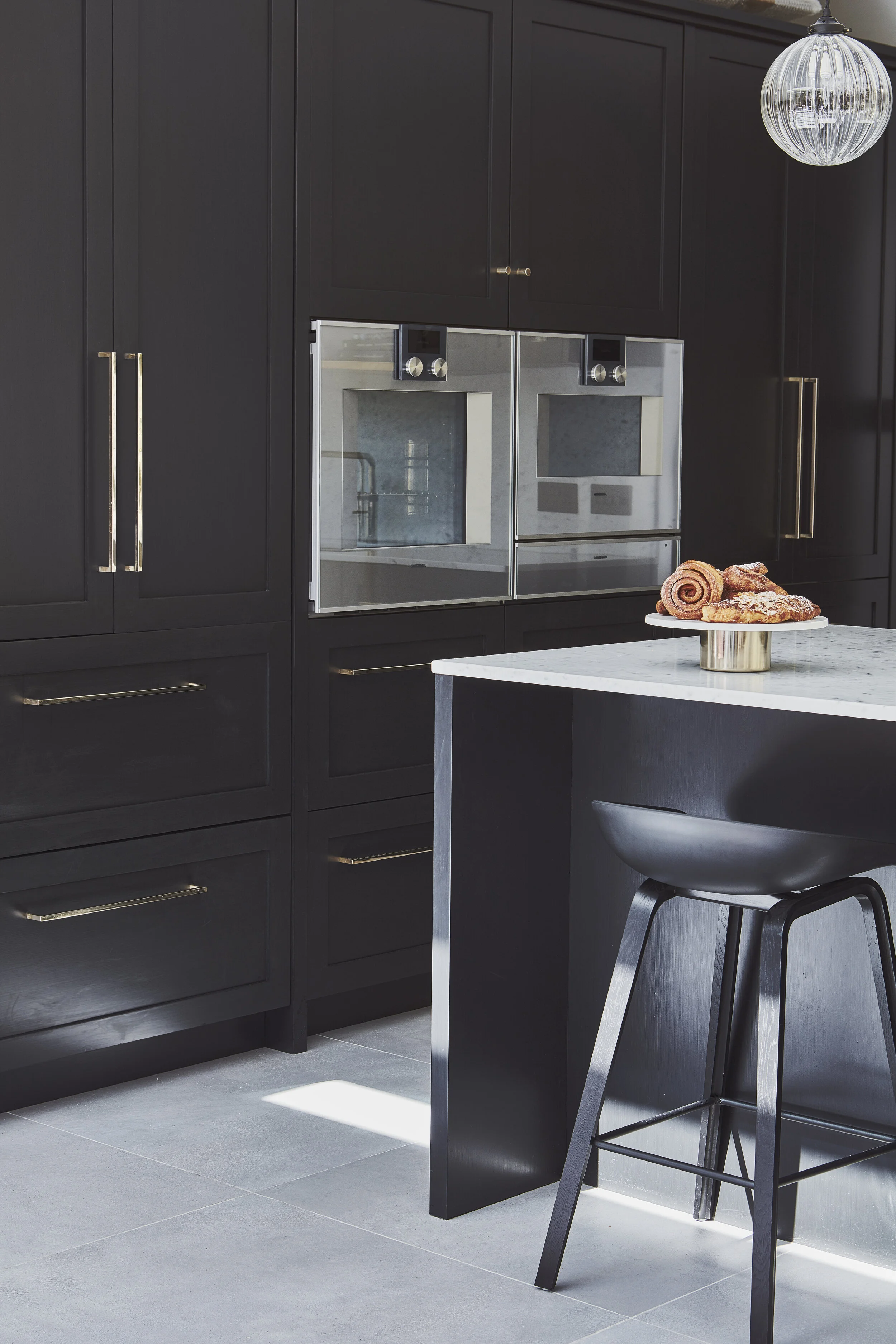 Kitchen design by Stanza interior design at this family home near Clapham Common. Dark cabinets with brass handles and two large built in ovens