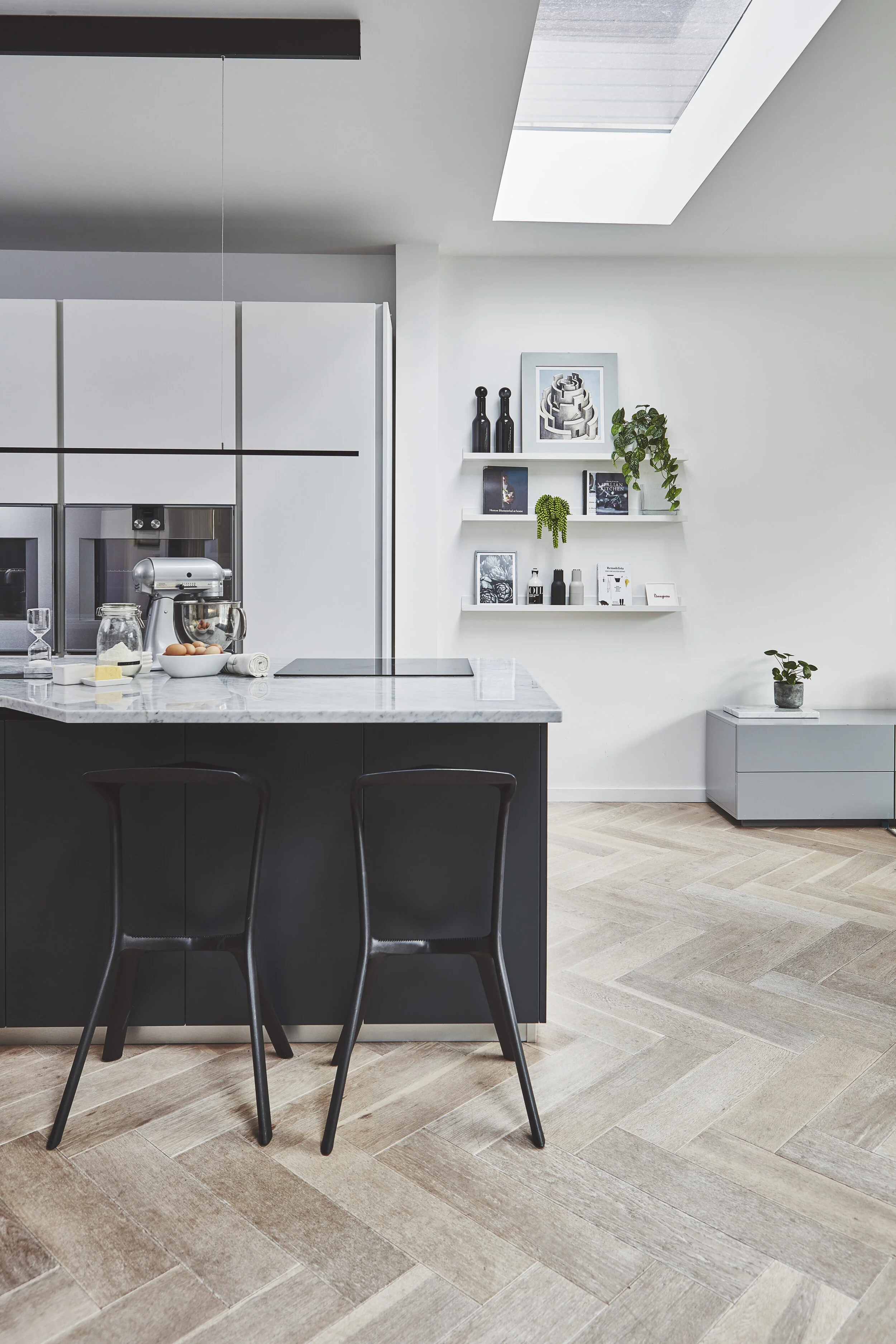 Herringbone wood flooring in this spacious open plan kitchen. Dark island with marble worktop, open shelving and bespoke cabinetry. Designed by Stanza interior design, based on Wandsworth Common