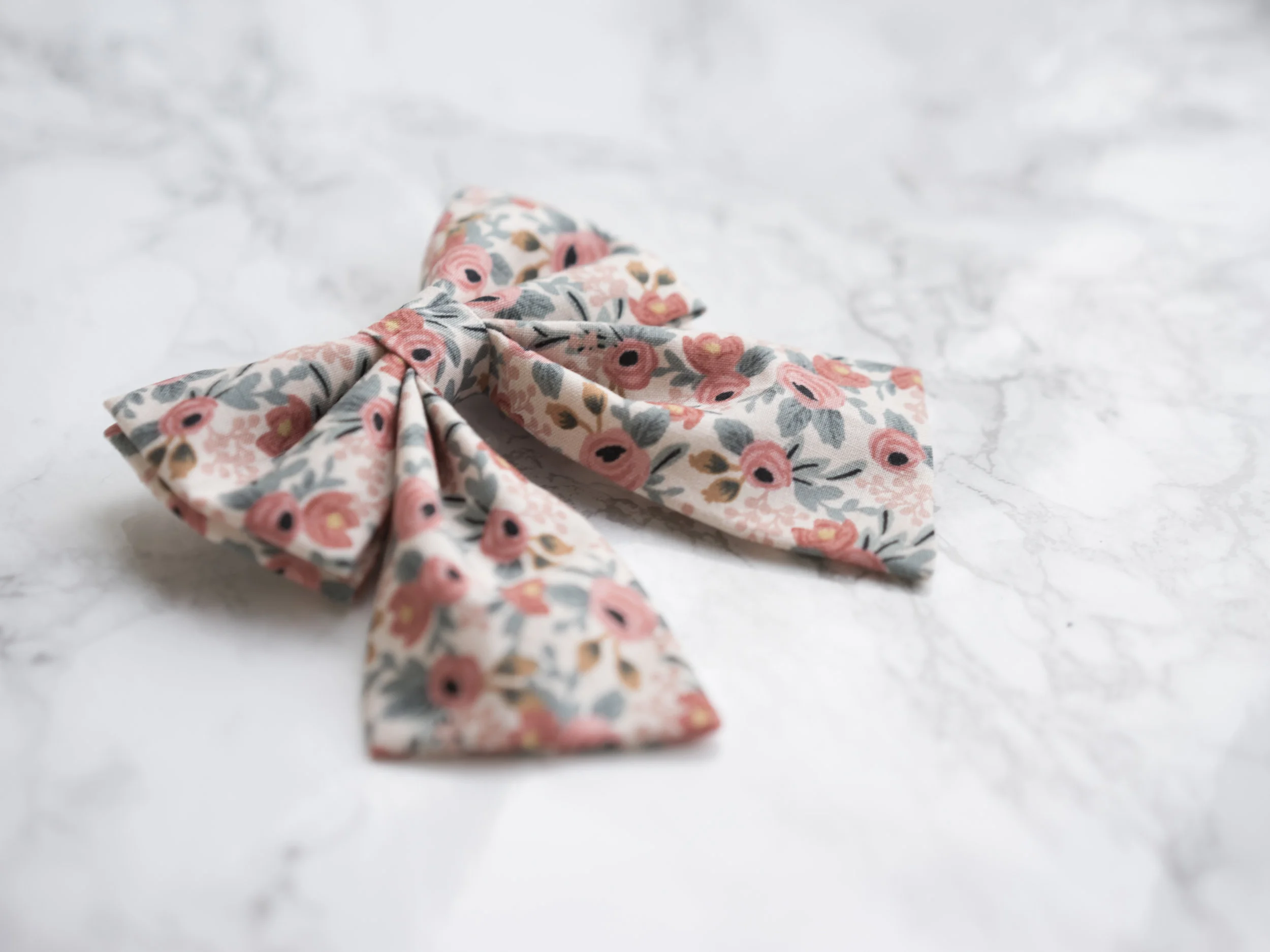 rifle paper co pink floral fabric cat sailor bow accessory on marble background