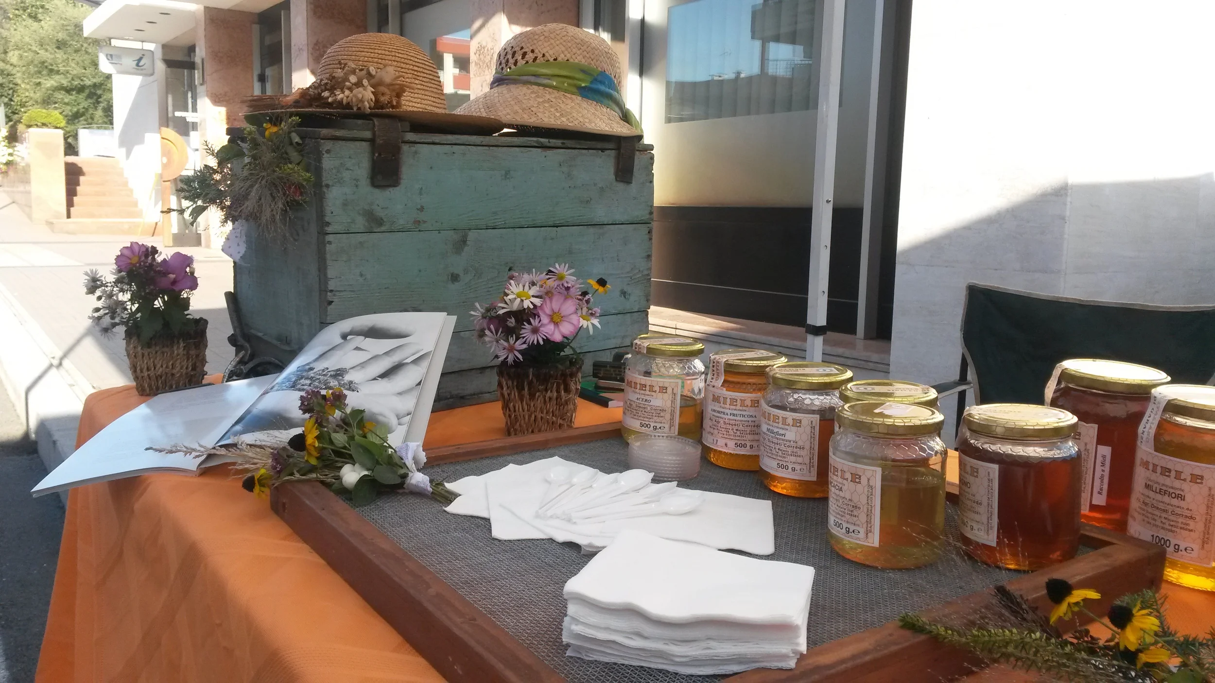 Siamo a metà Agosto, un ottimo raccolto e tanto miele da proporre. Parecchi clienti venivano in laboratorio a trovarci ma il nostro bisogno era quello di farci conoscere un po' di piu'....e così abbiamo preso la decisione.....un tavolino pieghevole, una tovaglia colorata, una vecchia arnia del nonno e il nostro miele......si parte!