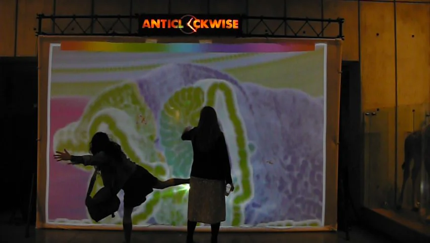 A collaborative digital canvas overflowing with watercolor-style paintings that you create with your movements. Every participant is given a unique color, which you change by reaching up to touch the palette across the top. Dance to enliven the backdrop. Cross paths with your friends to exchange & merge colors. Use your hands to make colorful finger puppets. 
