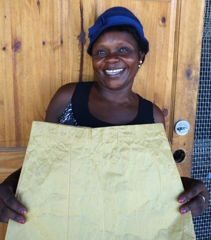 Terzilia is a student in our Mole St. Nicolas sewing program. She's holding up a sewing paper skirt, which is what they use to practice sewing on before using fabric.