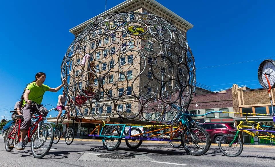 Volunteers moving a wheel dome by bike power. This sculpture was built by Free Cycles to be placed outside the Missoula Art Museum.