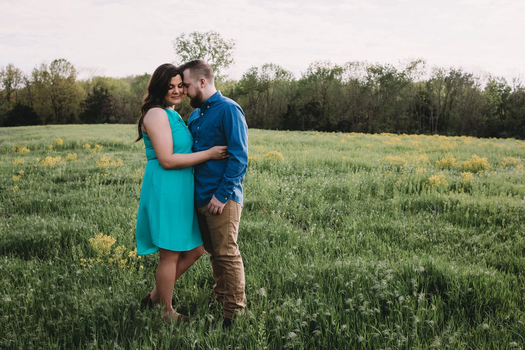 Couple embrace in field of wildflowers during engagement photos in Kansas City.