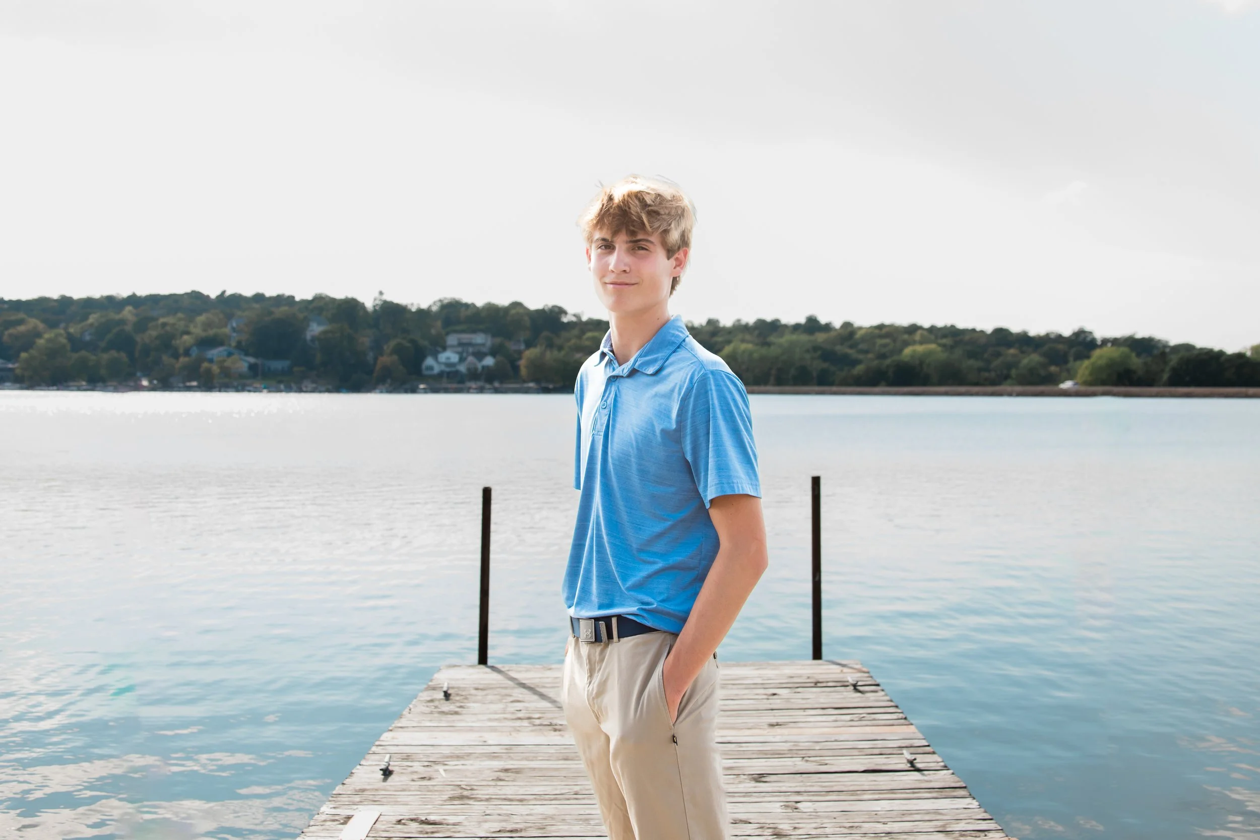 Graduate stands on dock by Lake Olathe duiring senior photos in Kansas City.