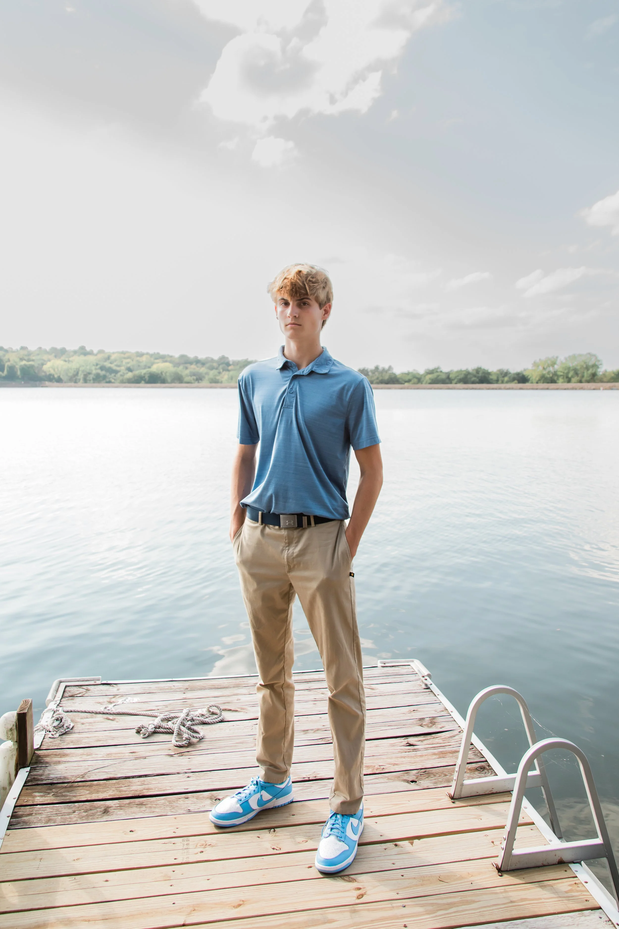 Senior male stands by lake during senior photos in Kansas City.