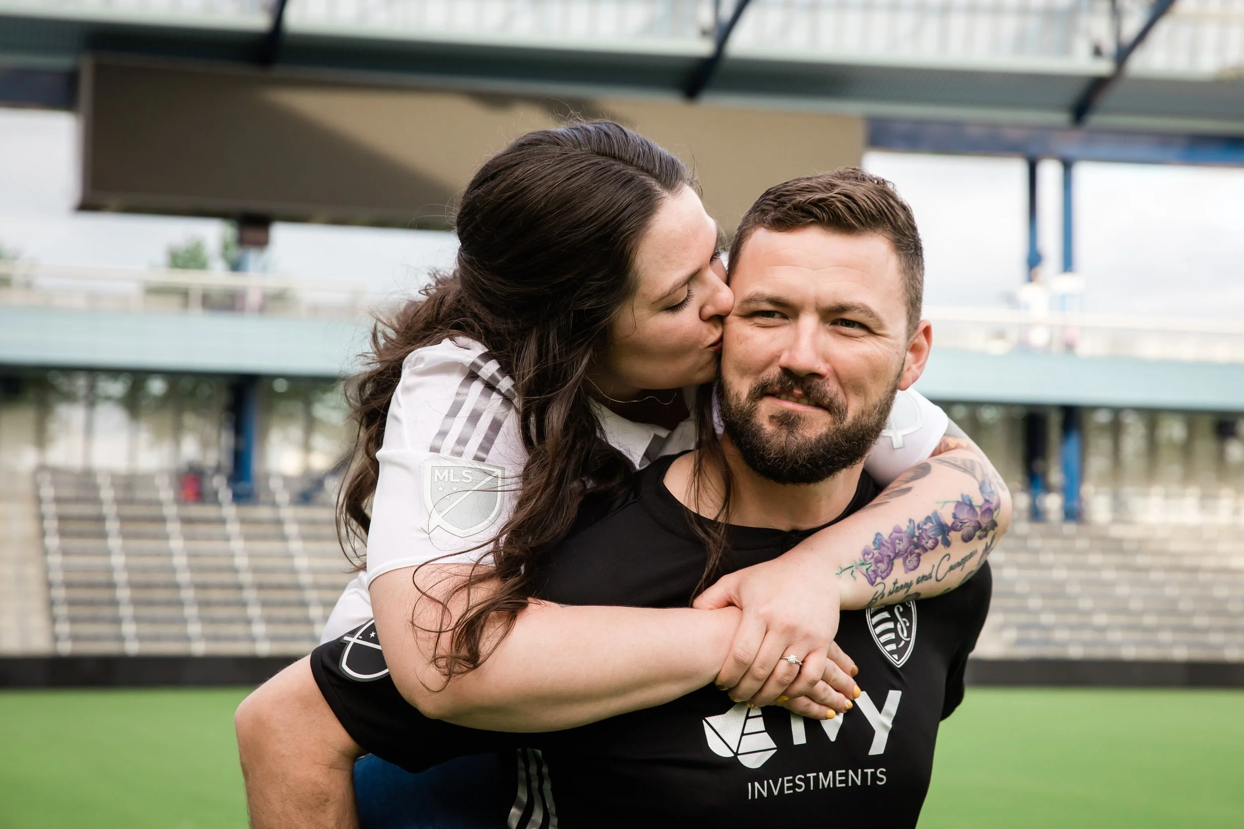 Engaged couple kiss on field of Sporting KC during engagement photos in Kansas City.