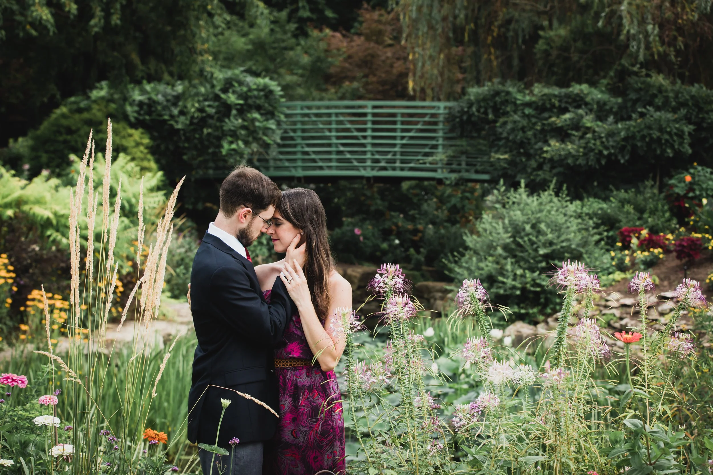 Couple embraces during engagement photos in flower garden at the Overland Park Arboretum.