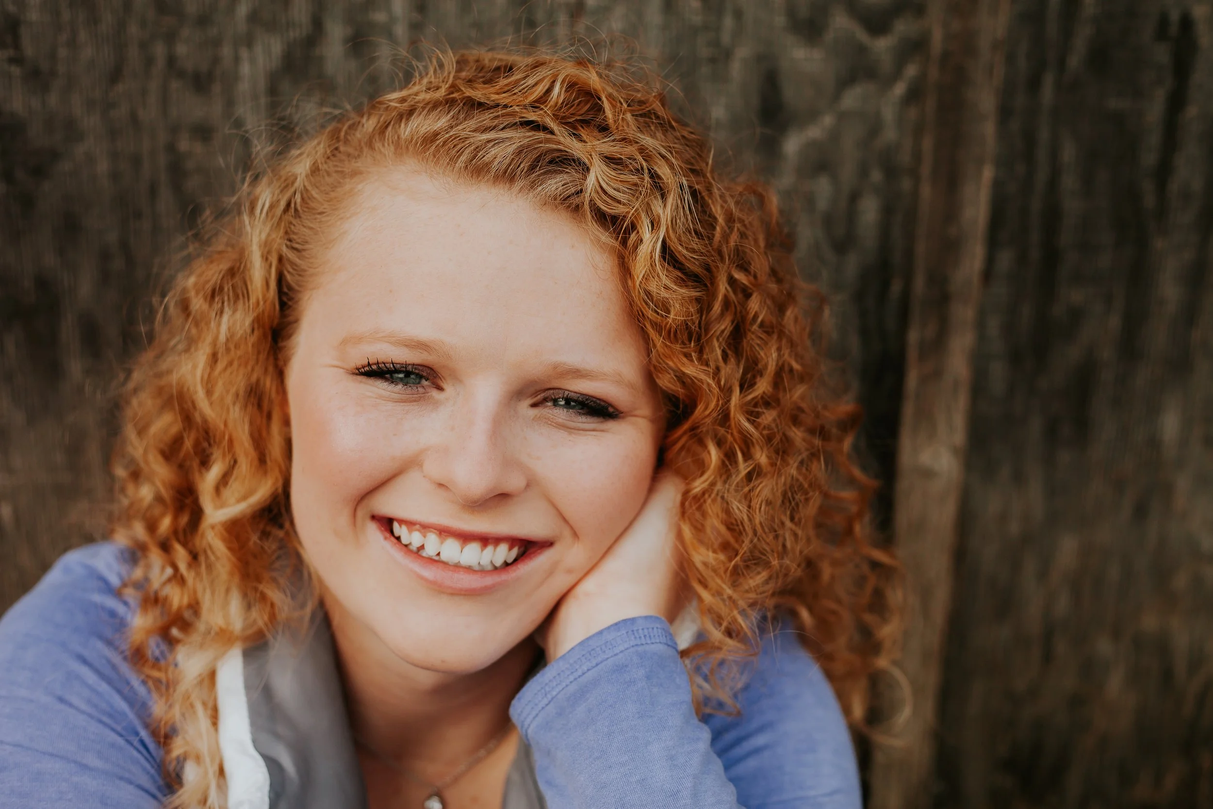 Senior girl smiles during rustic senior photo session in Liberty, MO.