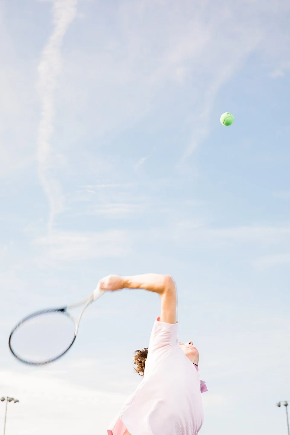 Action shot of senior boy serving tennis during senior photography session in Kearney, Missouri.