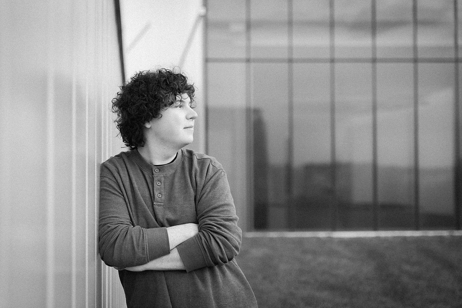 Senior boy leans against the wall on the roof of the Nelson Atkins museum during senior photos in Kansas City.